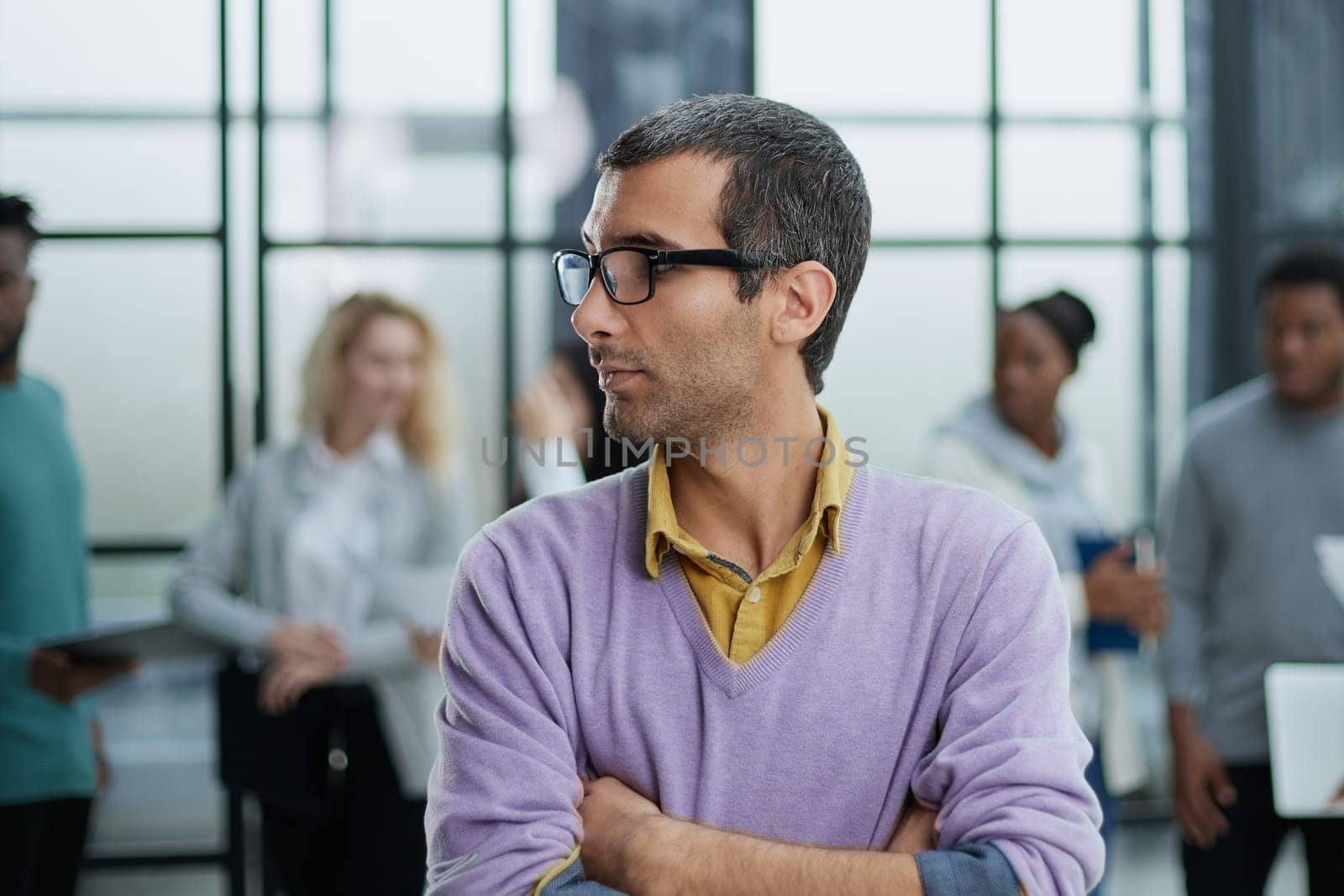 Young handsome businessman looks to the side against the background of his colleagues