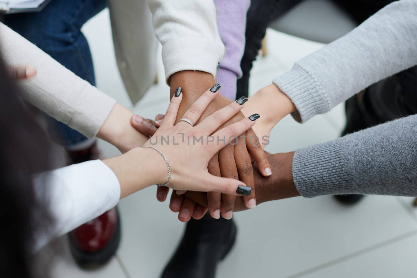 Diverse people sitting in circle holding hands at group therapy by Prosto