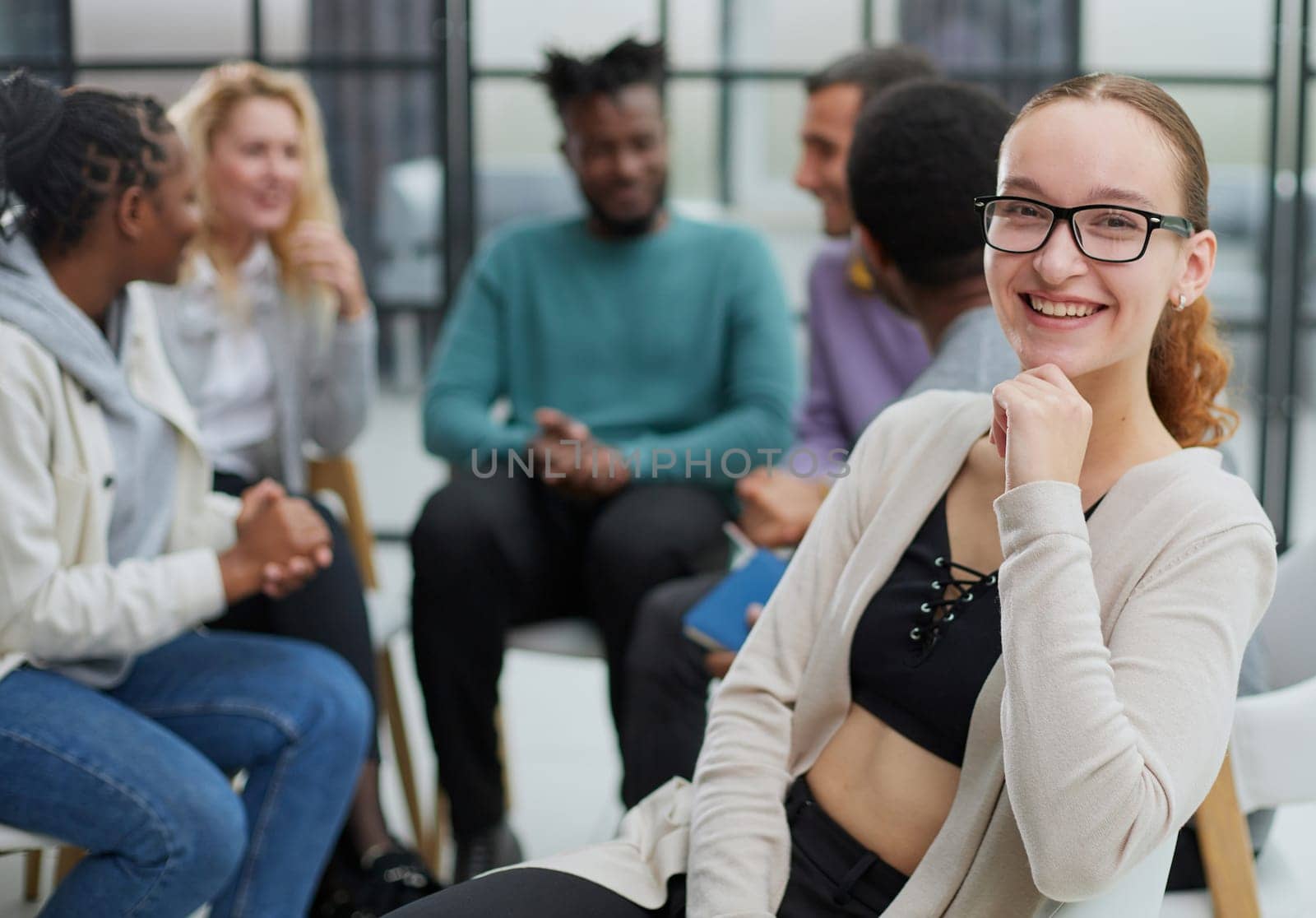 Smiling businesswoman looking at camera at seminar with her colleagues near by