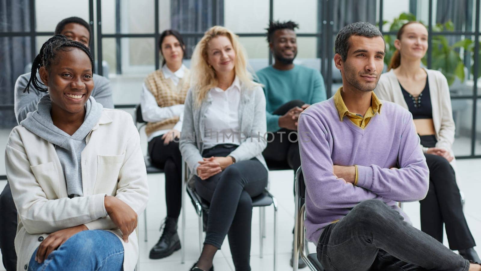 diverse young people sitting on chairs in the conference room.