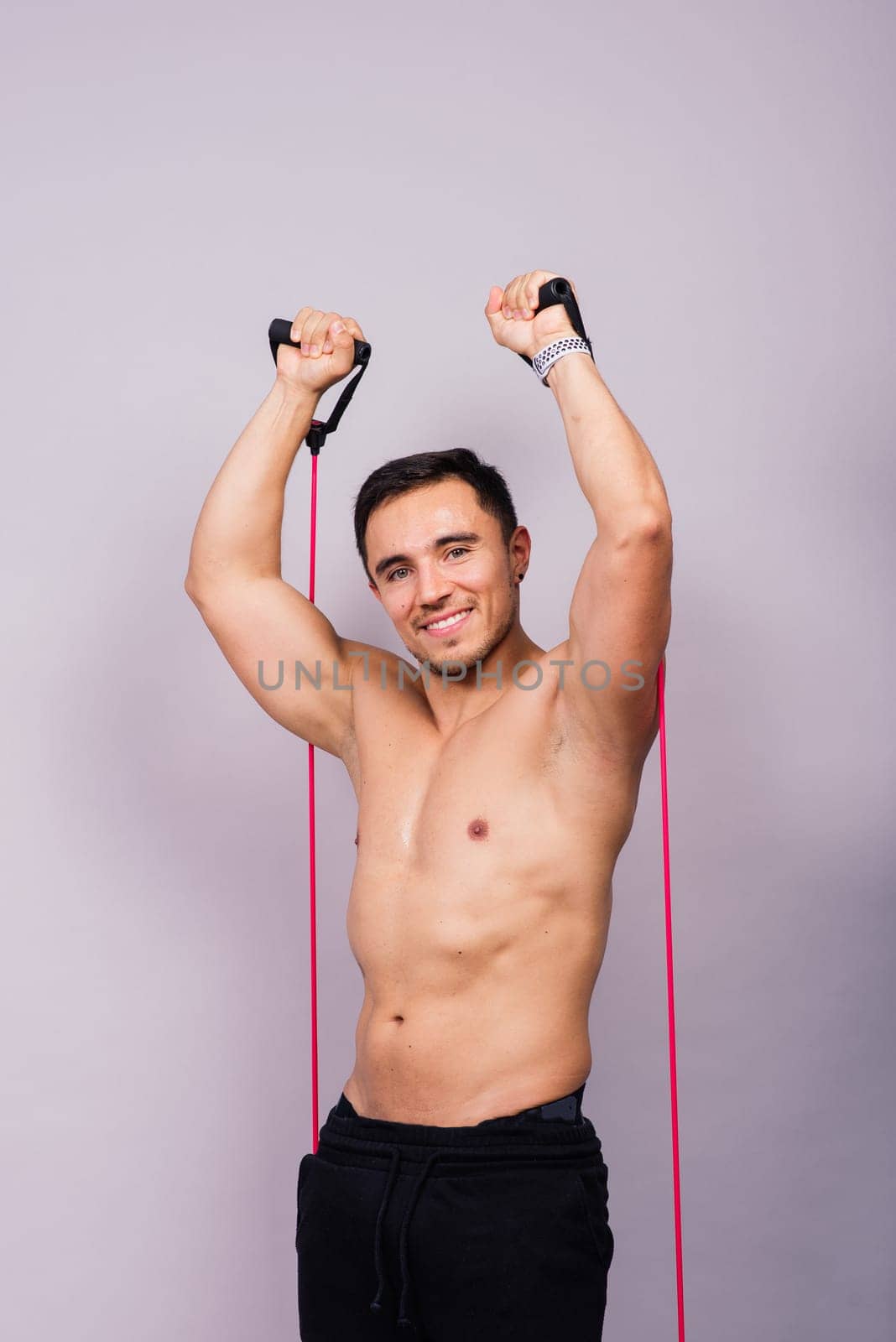 Athletic man skipping with a jump rope on grey background. Best cardio workout by Zelenin