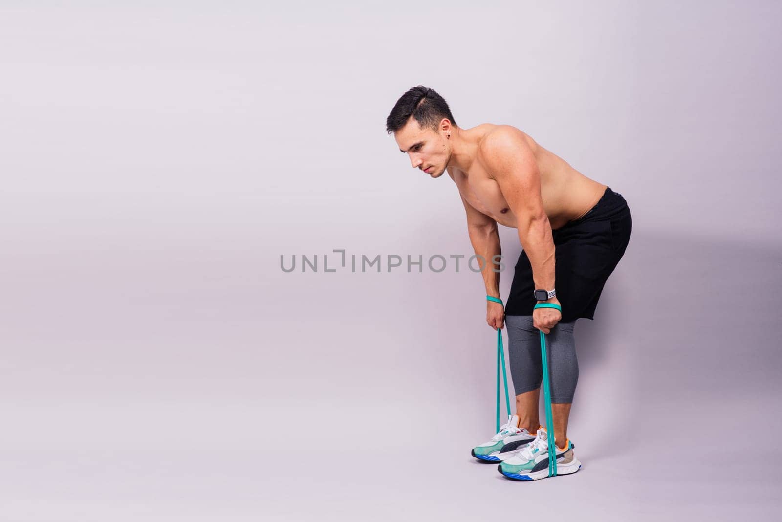 Athletic man skipping with jump rope on grey background. Best cardio workout