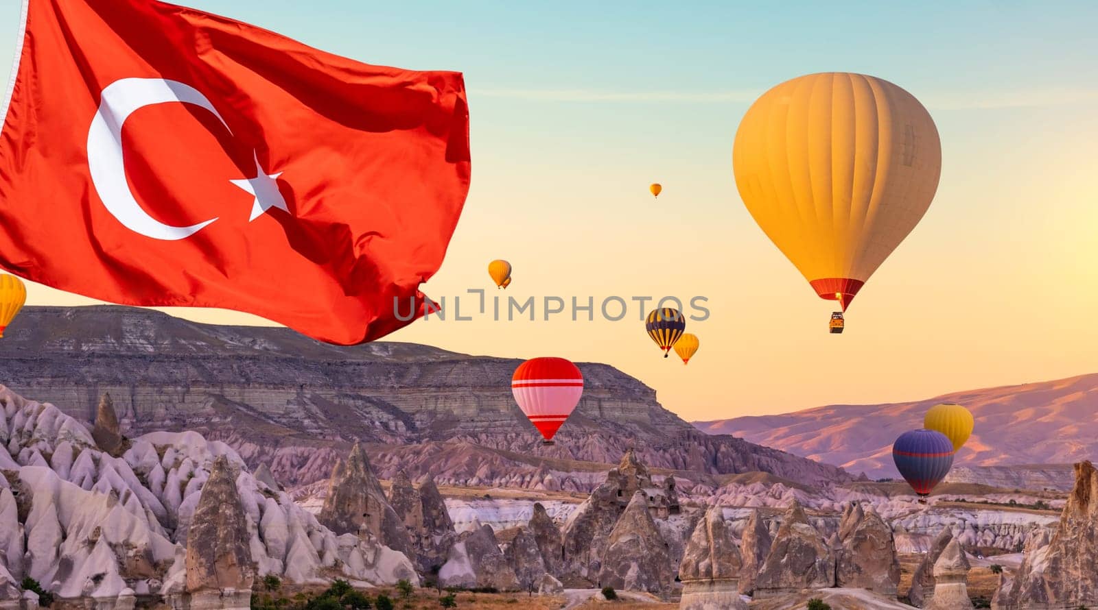 Turkey flag against hot air balloons in sunset sky floating over mountains