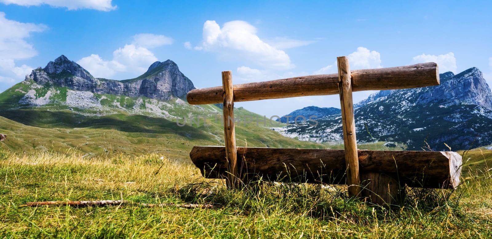 Scenic wooden bench in mountains of Montenegro in National park Durmitor. Amazing north balkan nature landscape in sunny summer day with blue sky and clouds