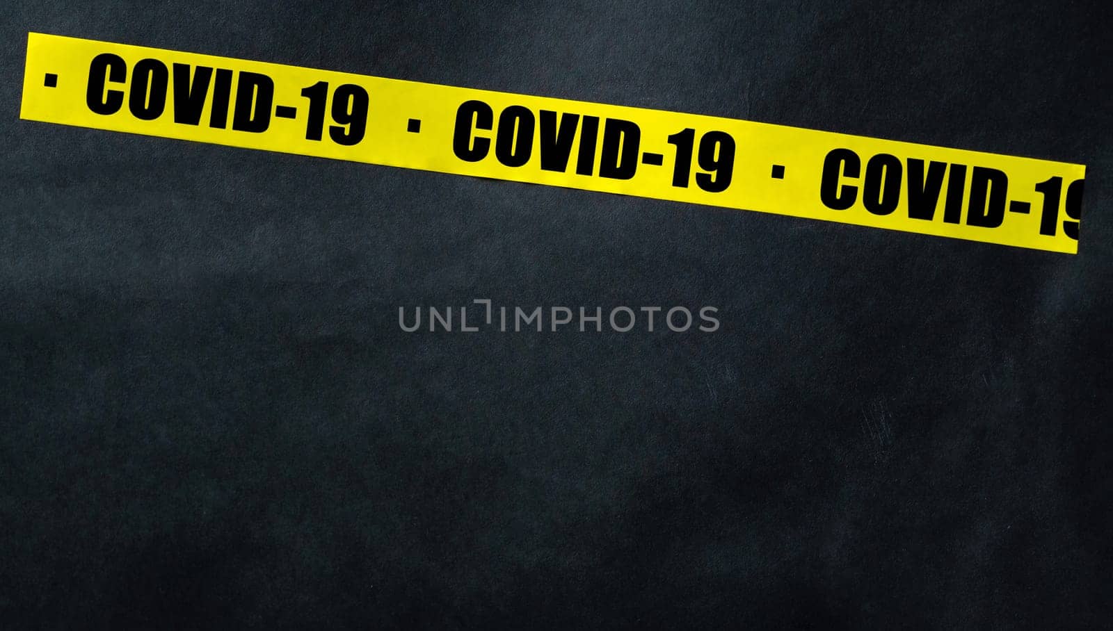 Yellow tape with text COVID-19 on a dark background. Warning ribbon.