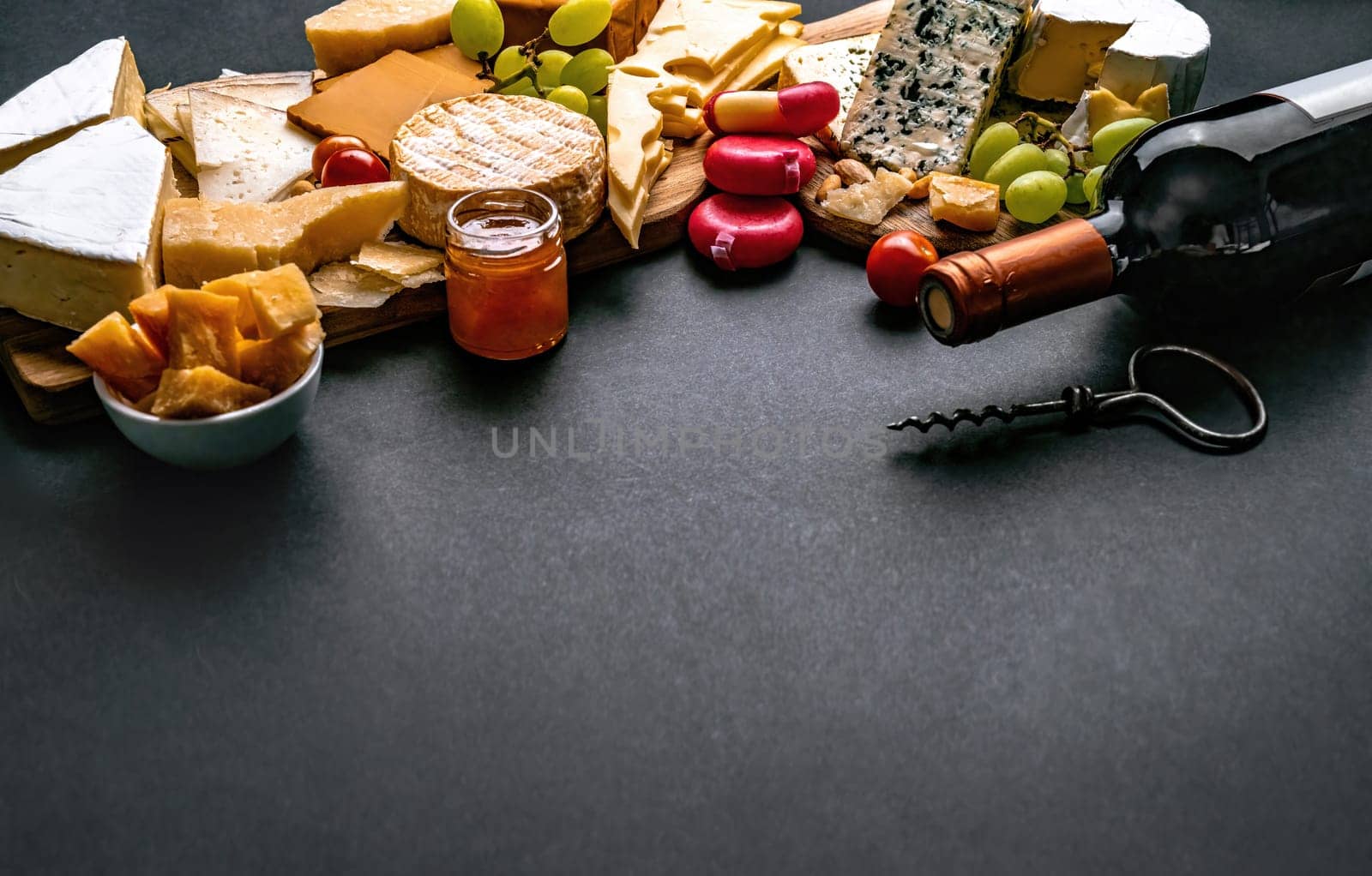 Different kinds of cheese served with wine bottle for gourmet nutrition. Organic parmesan and brie set with grape alcohol delicatessen