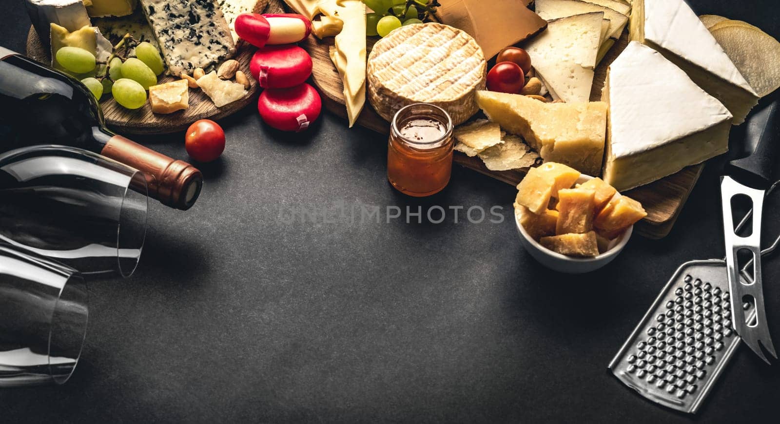 Different kinds of cheese served with wine bottle, glasses and grape for gourmet nutrition. Organic parmesan and brie set with alcohol composition