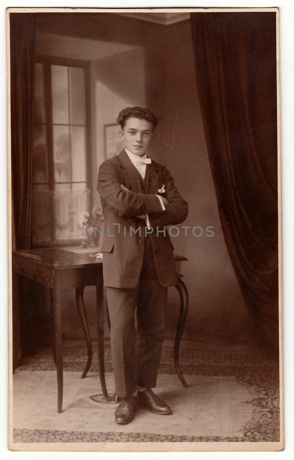 Vintage photo shows young man poses in the room. Antique black white studio portrait. by roman_nerud