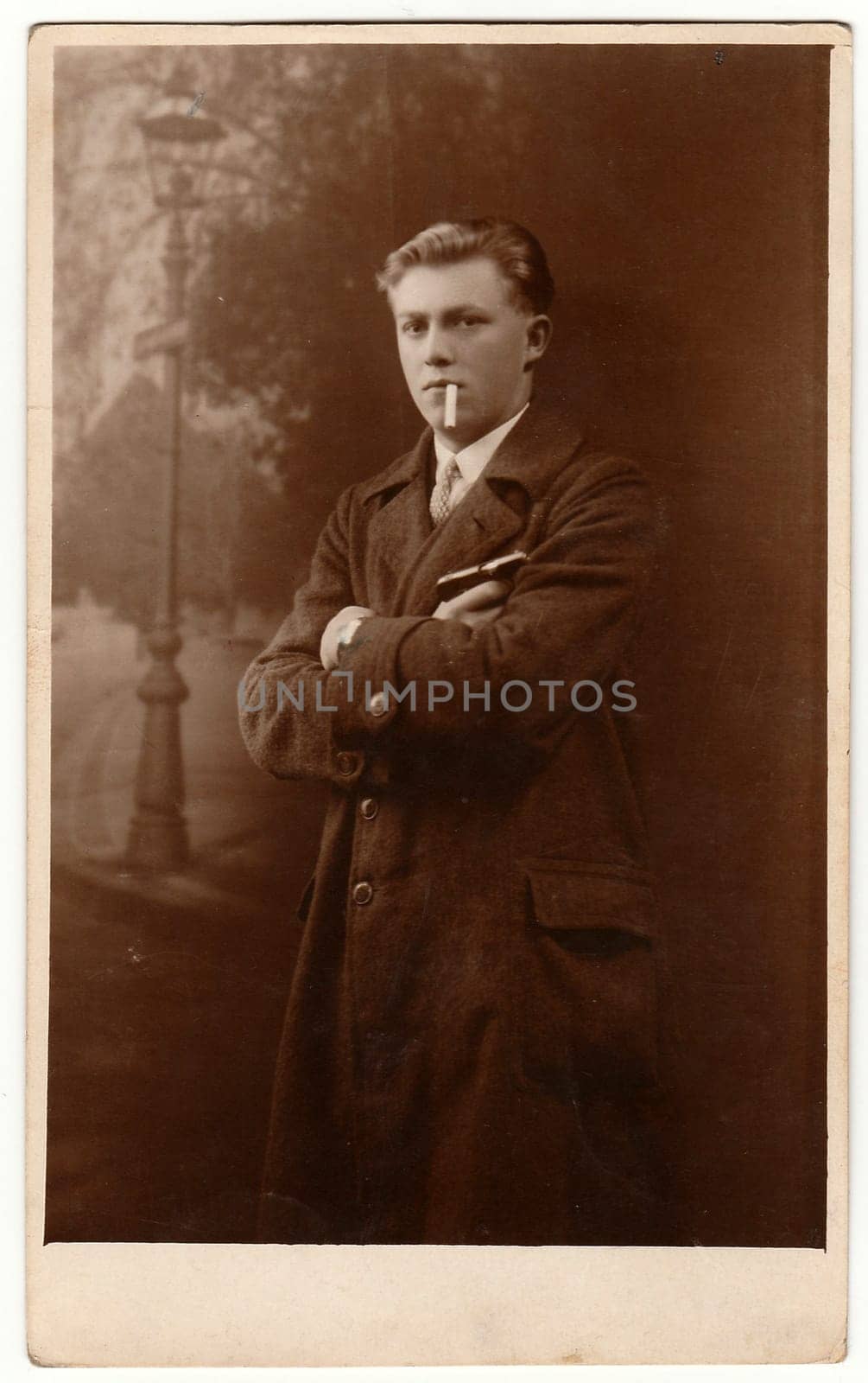 LIBEREC (REICHENBERG), THE CZECHOSLOVAK REPUBLIC - CIRCA 1920s: Vintage photo shows young man poses with cigarette outdoors. Antique black white portrait.