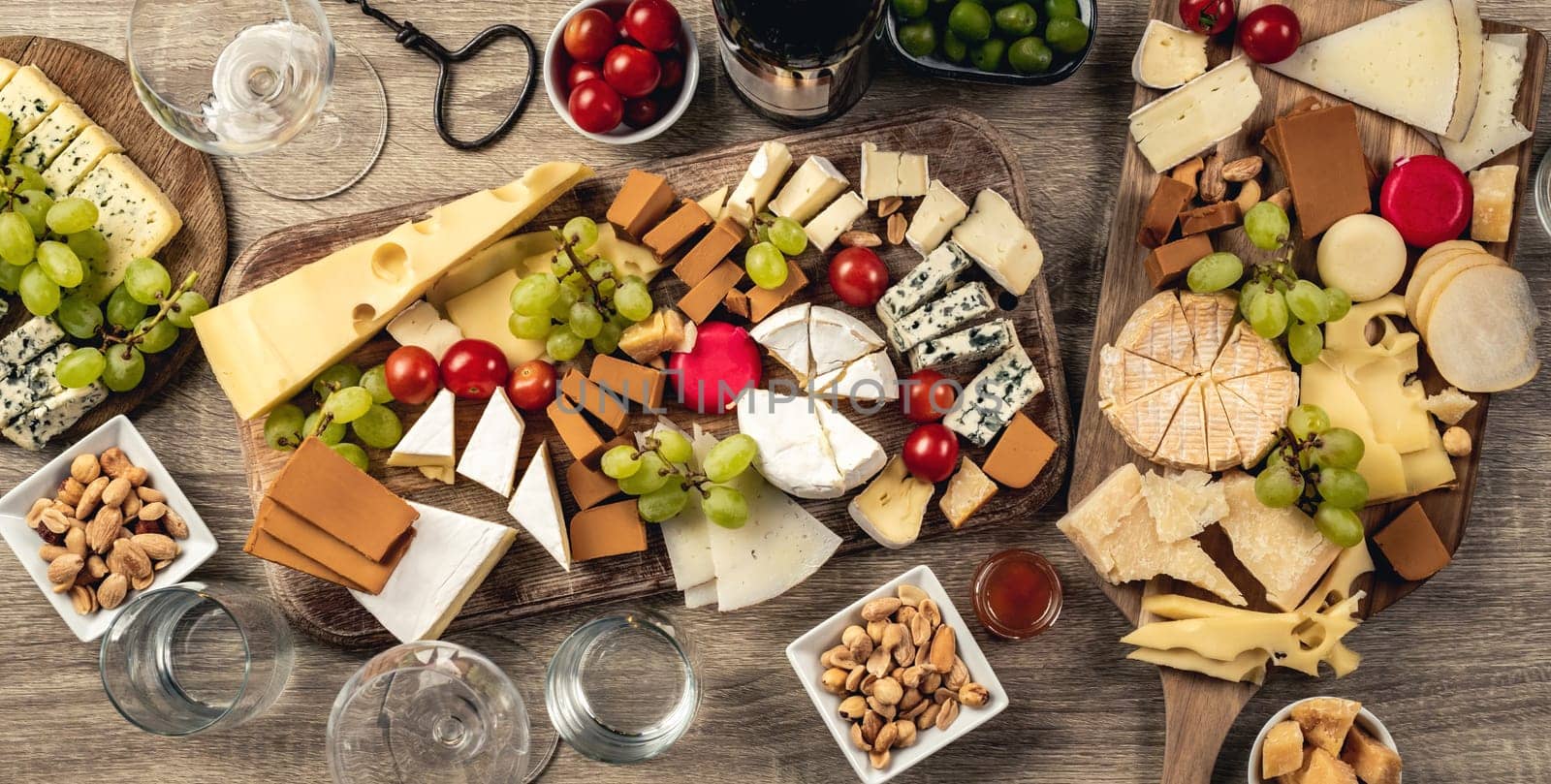 Variety of cheese kinds served with grape, honey and olives for gourmet nutrition. Organic parmesan, brie and camambert set with nuts