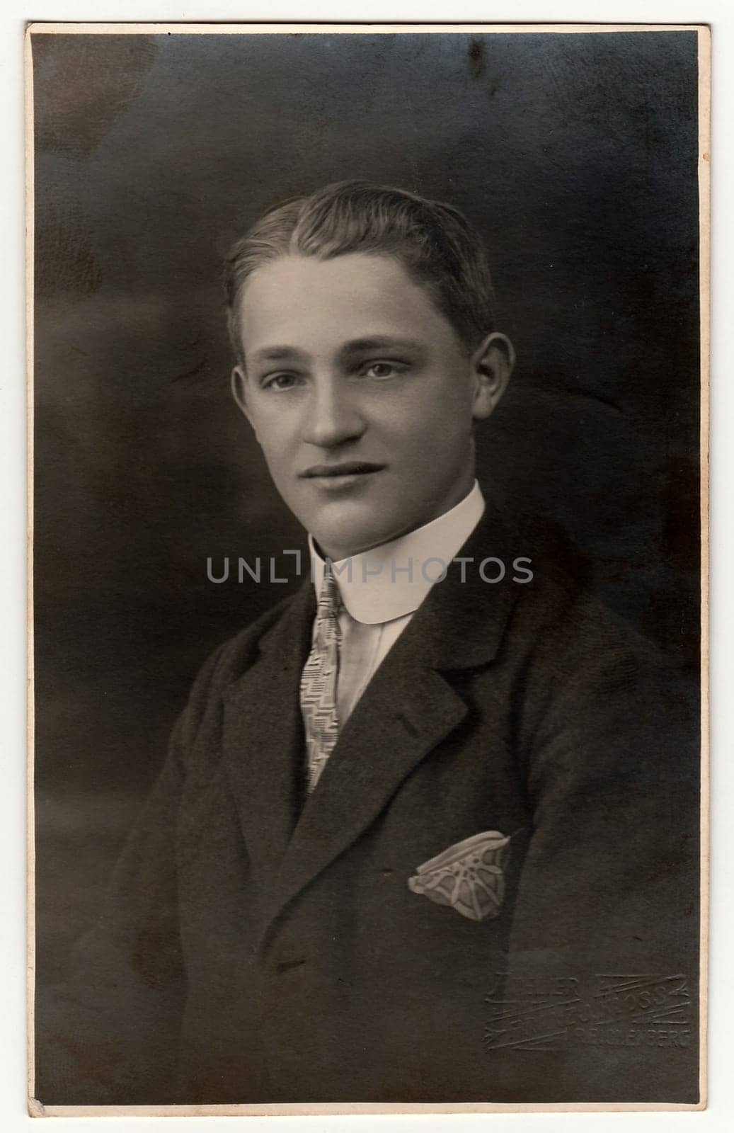 LIBEREC (REICHENBERG), THE CZECHOSLOVAK REPUBLIC - CIRCA 1920s: Vintage photo shows young man wears jacket with handkerchief in the pocket. Antique black white studio portrait.