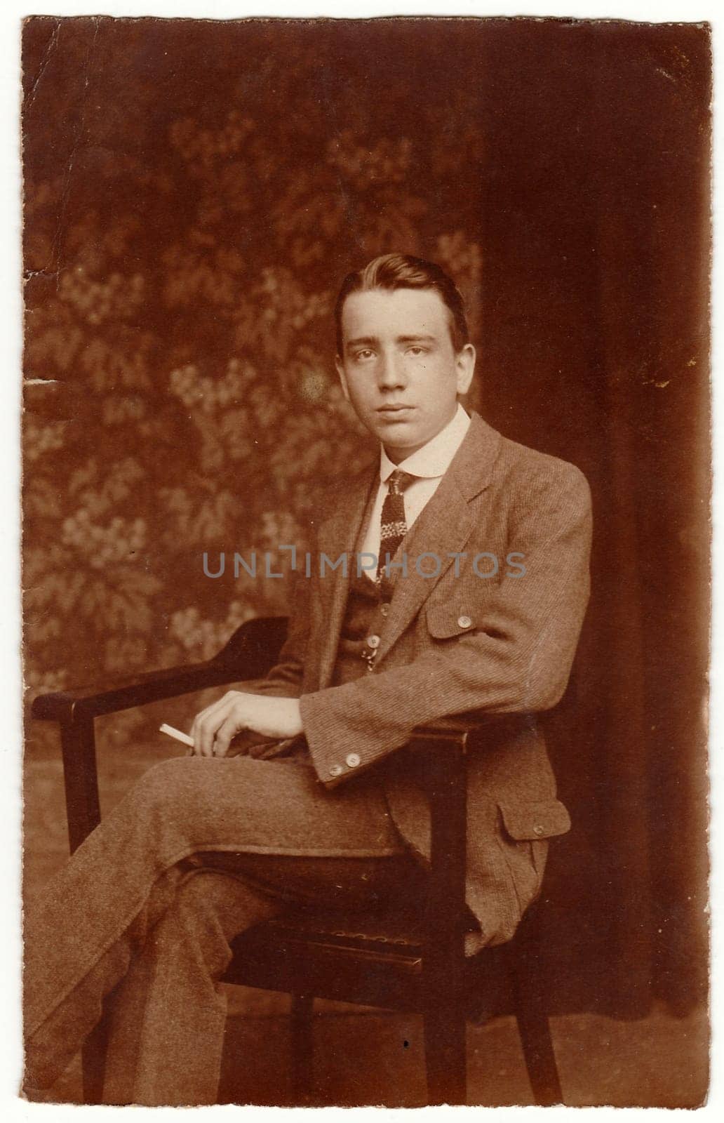 THE CZECHOSLOVAK REPUBLIC - CIRCA 1920s: Vintage photo shows man sits on the chair. Black white studio portratit with sepia tint