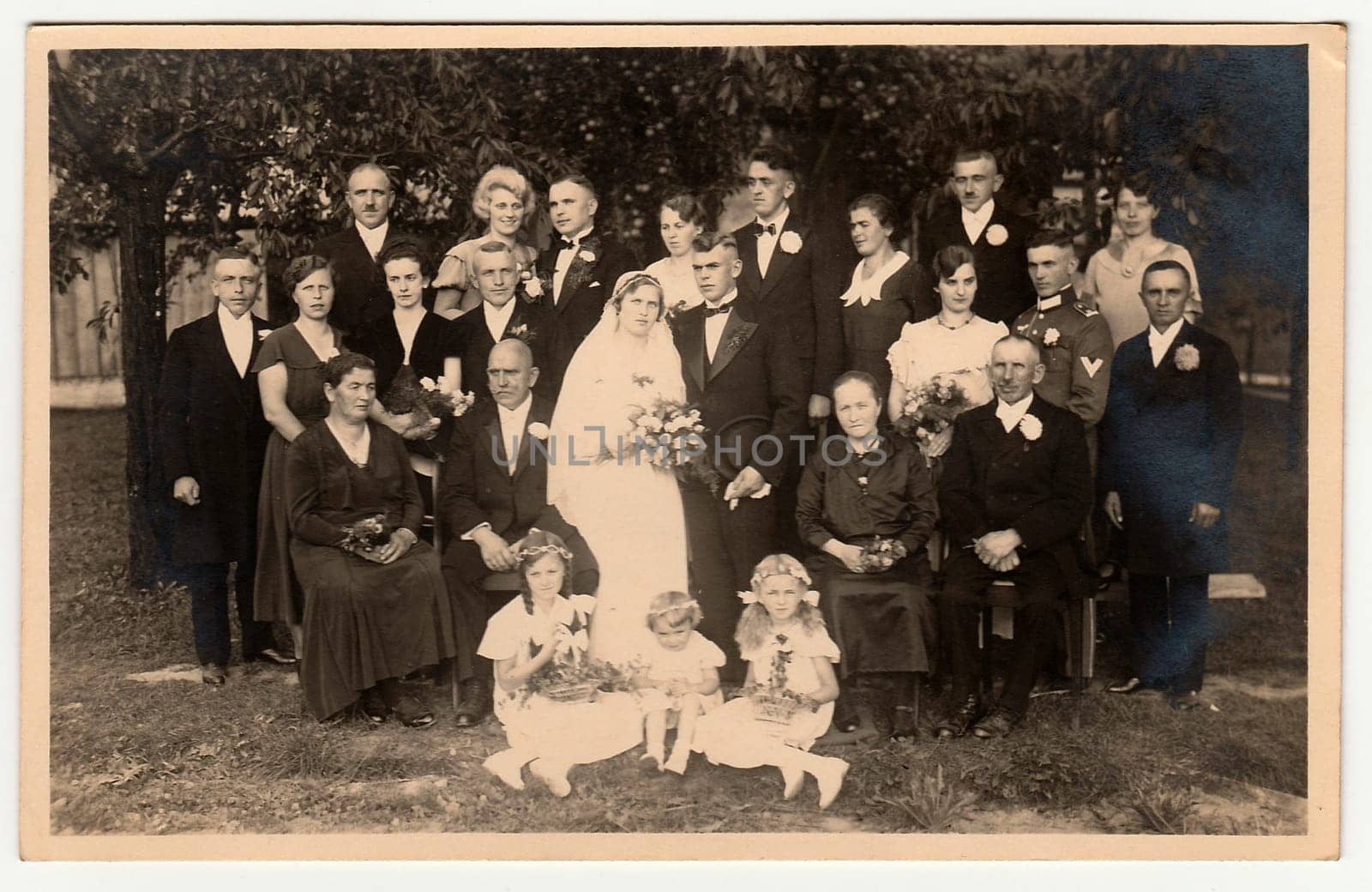 Vintage photo shows newlyweds with wedding guests. Photo was taken in the summer garden. Black white photo. by roman_nerud