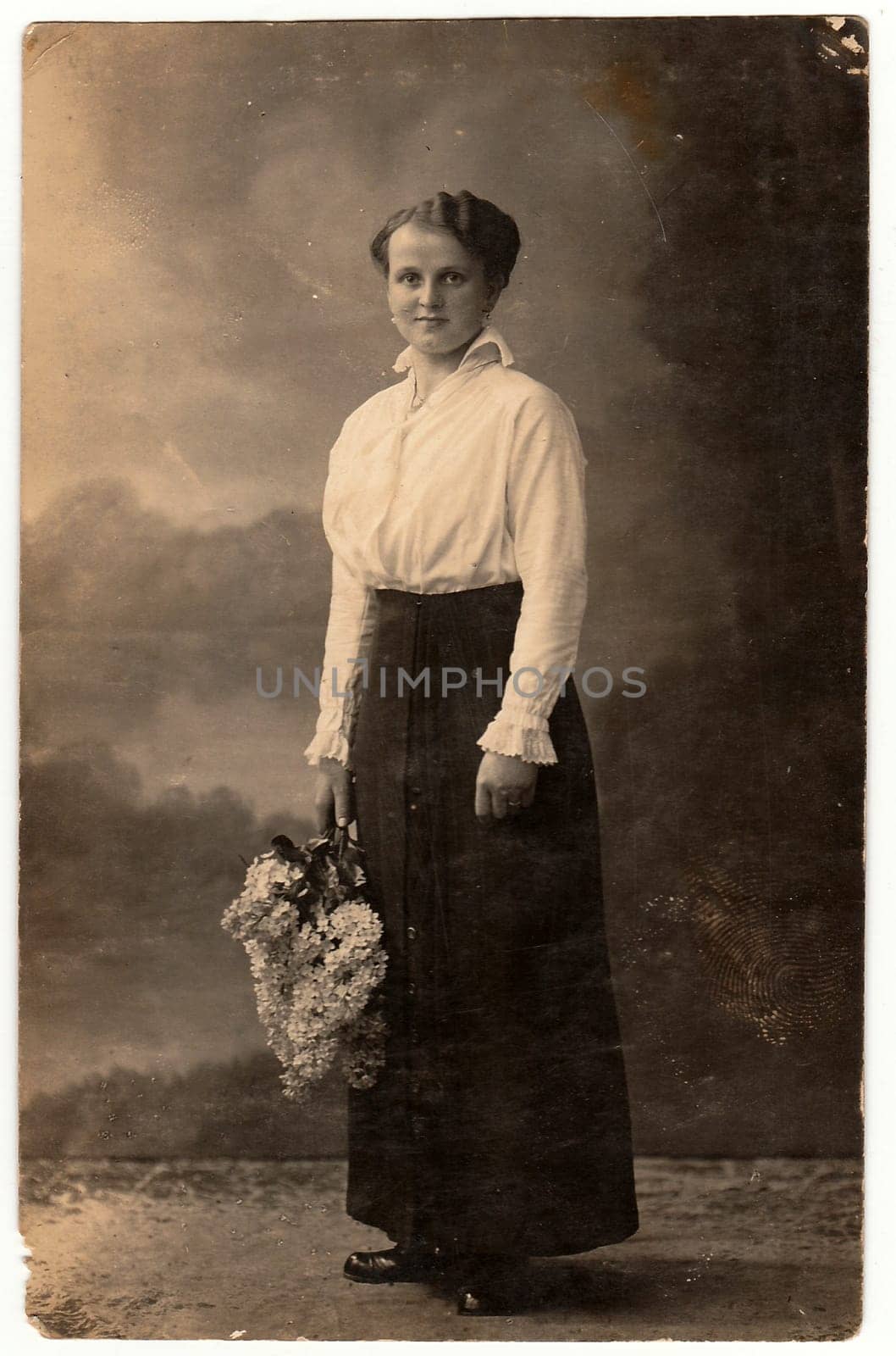 SOLINGEN, GERMANY - CIRCA 1920s: Vintage photo shows woman holds a bunch of lilac. Black white photo with sepia tint.