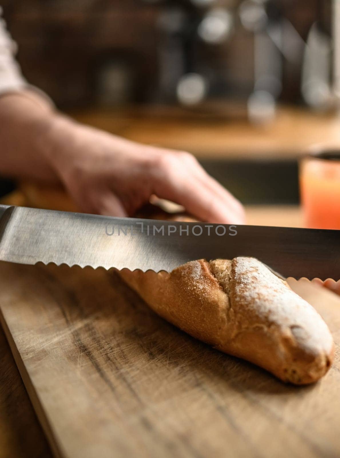 Girl hand cut french baguette with knife at kitchen. Tasty rustic fresh bread from for breakfast meal