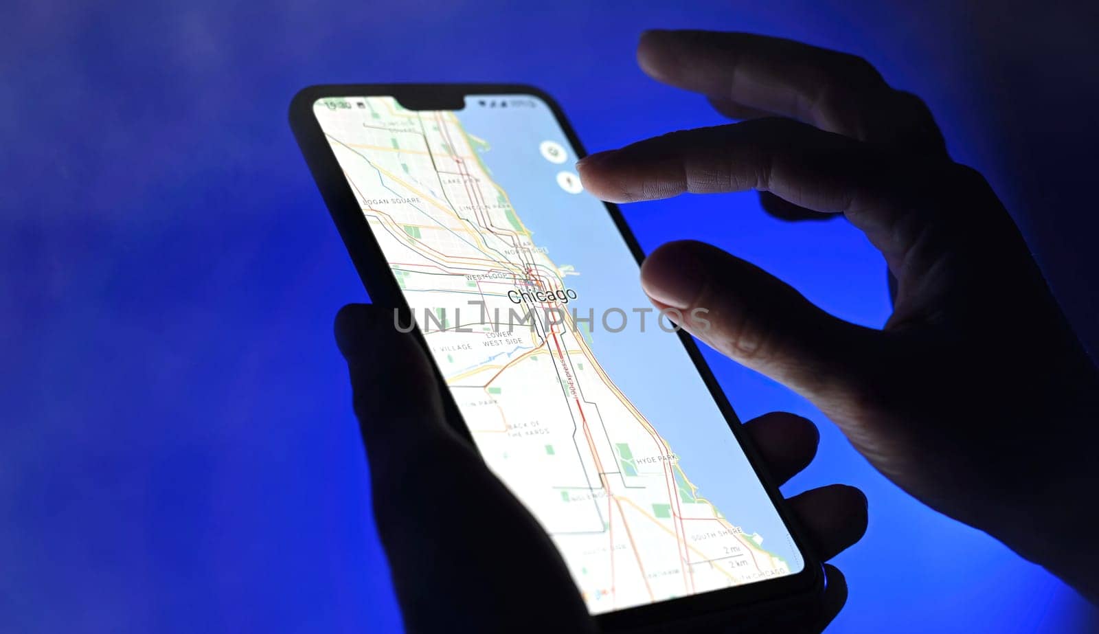 Poznan, Poland - 13 January: Girl using google maps app on a smartphone against blue background, close up view. Chicago city streets.