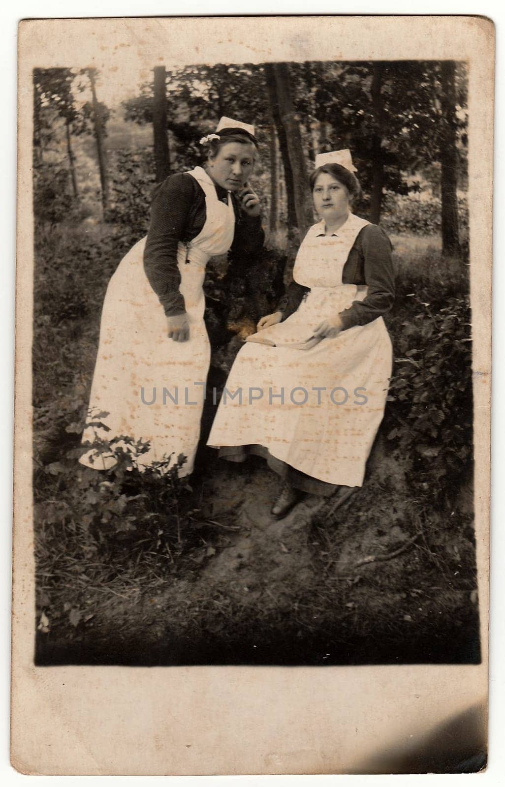 Vintage photo shows two nurses outdoors. Antique black & white photo with dark tint obtained during photo process. by roman_nerud