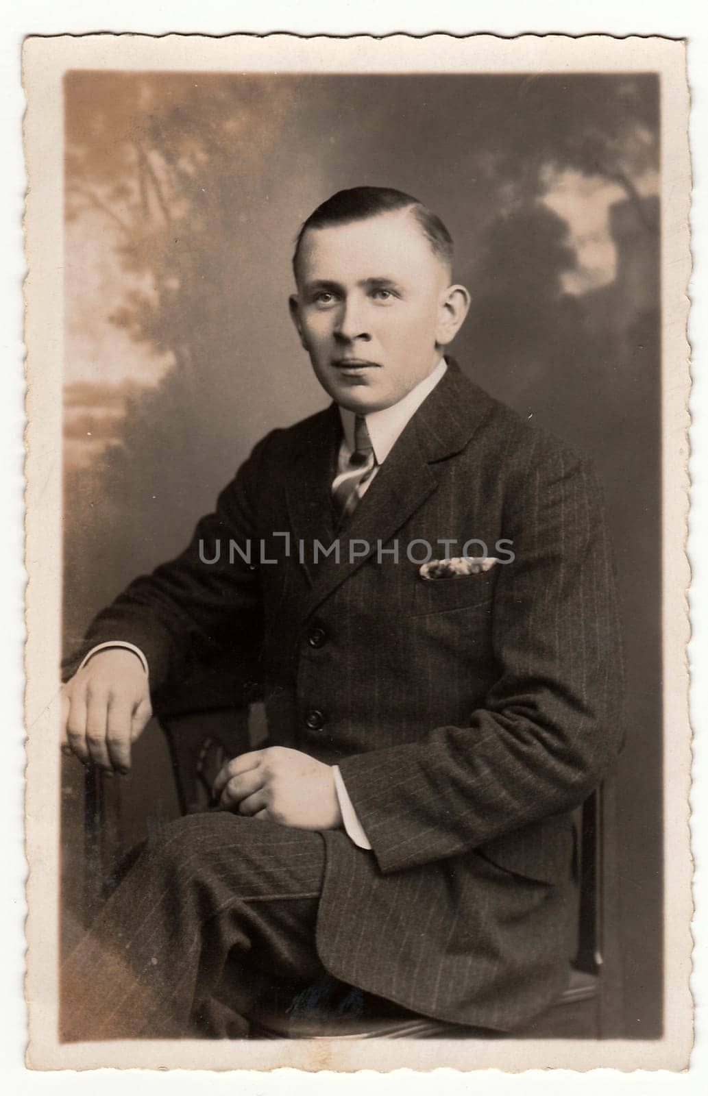 EILENBURG, GERMANY - CIRCA 1920s: Vintage photo shows young man poses in a photography studio. Antique black & white studio portrait.