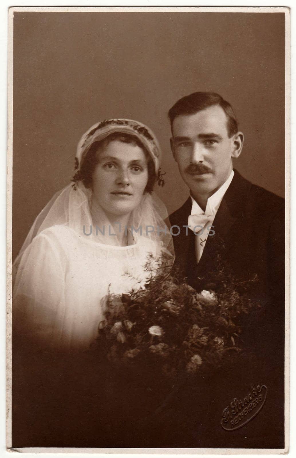 LIBEREC (REICHENBERG), THE CZECHOSLOVAK REPUBLIC - CIRCA 1930s: Vintage photo of newlyweds. Bride wears a veil. Black & white antique studio portrait.