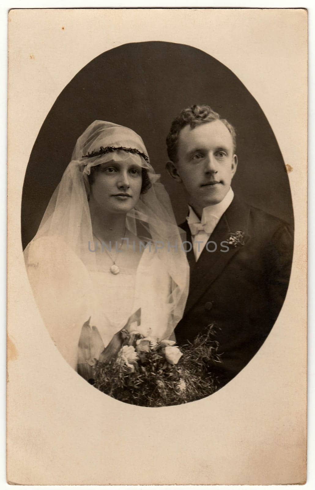Vintage photo of newlyweds. Bride wears a veil. Black white antique studio portrait. Photo is oval shape. by roman_nerud