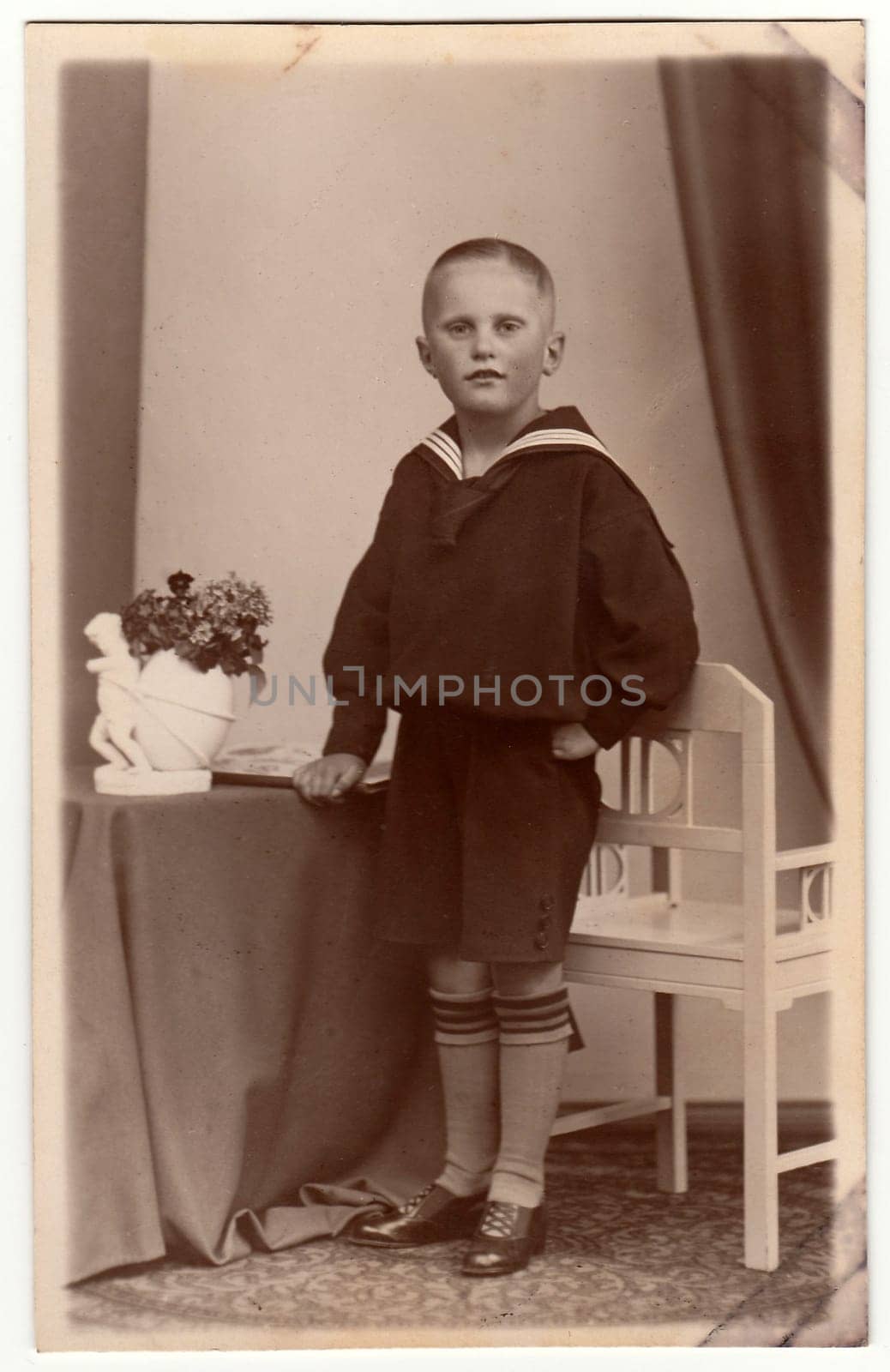 LEIPZIG, GERMANY - CIRCA 1930s: Vintage photo shows a young boy wears sailor costume. Black white antique studio portrait.