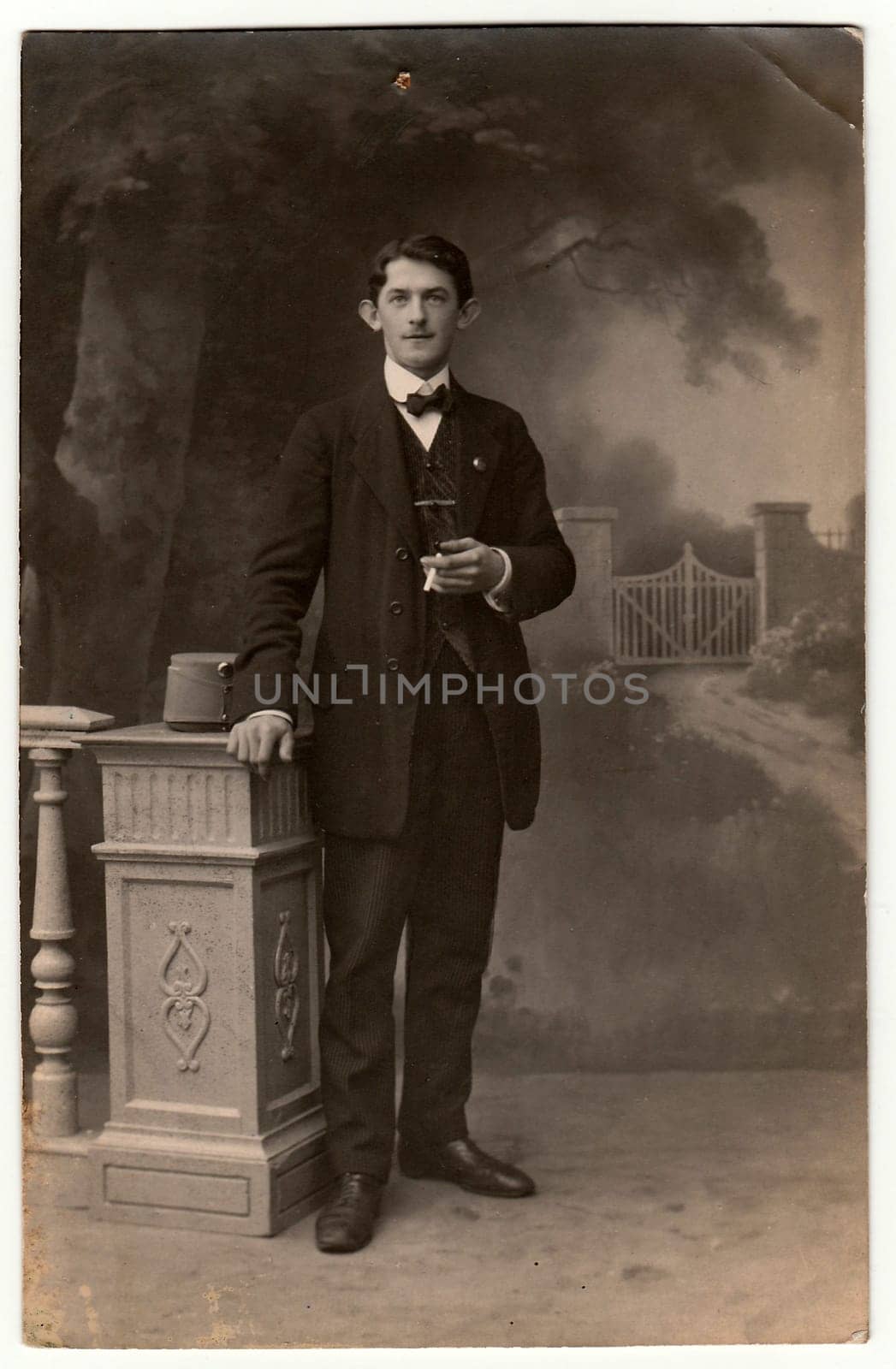 Vintage photo shows man with cigarette poses in a photography studio. Photo with dark sepia tint. Black white studio portrait. by roman_nerud