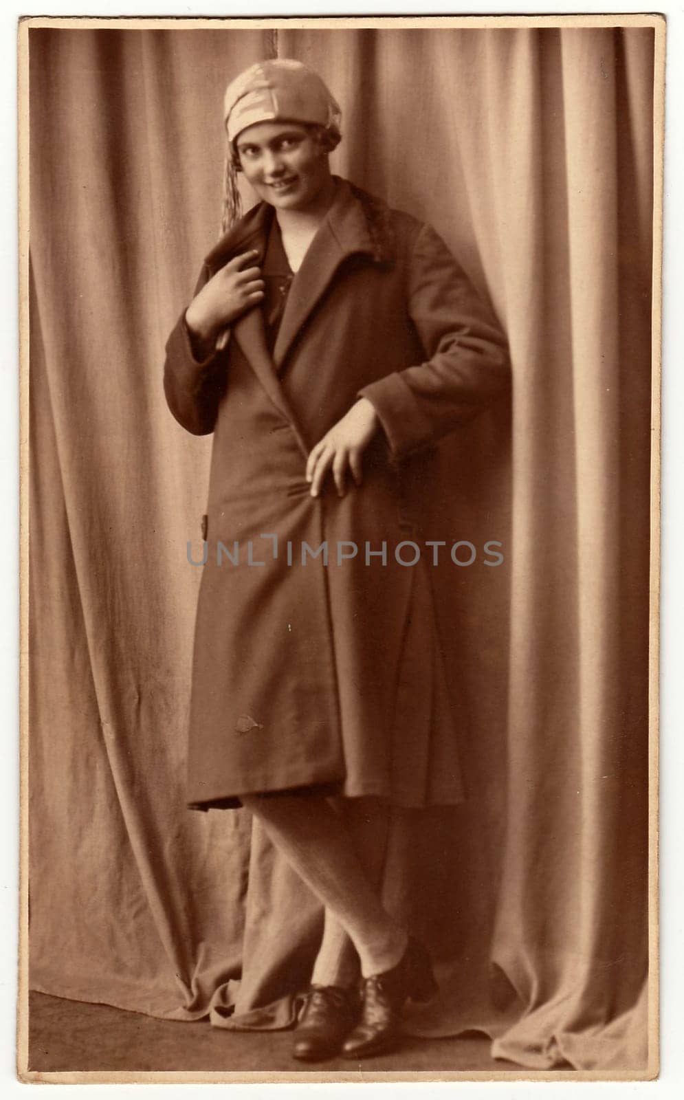 Vintage photo shows woman poses in a photography studio. Photo with dark sepia tint. Black white studio portrait. by roman_nerud