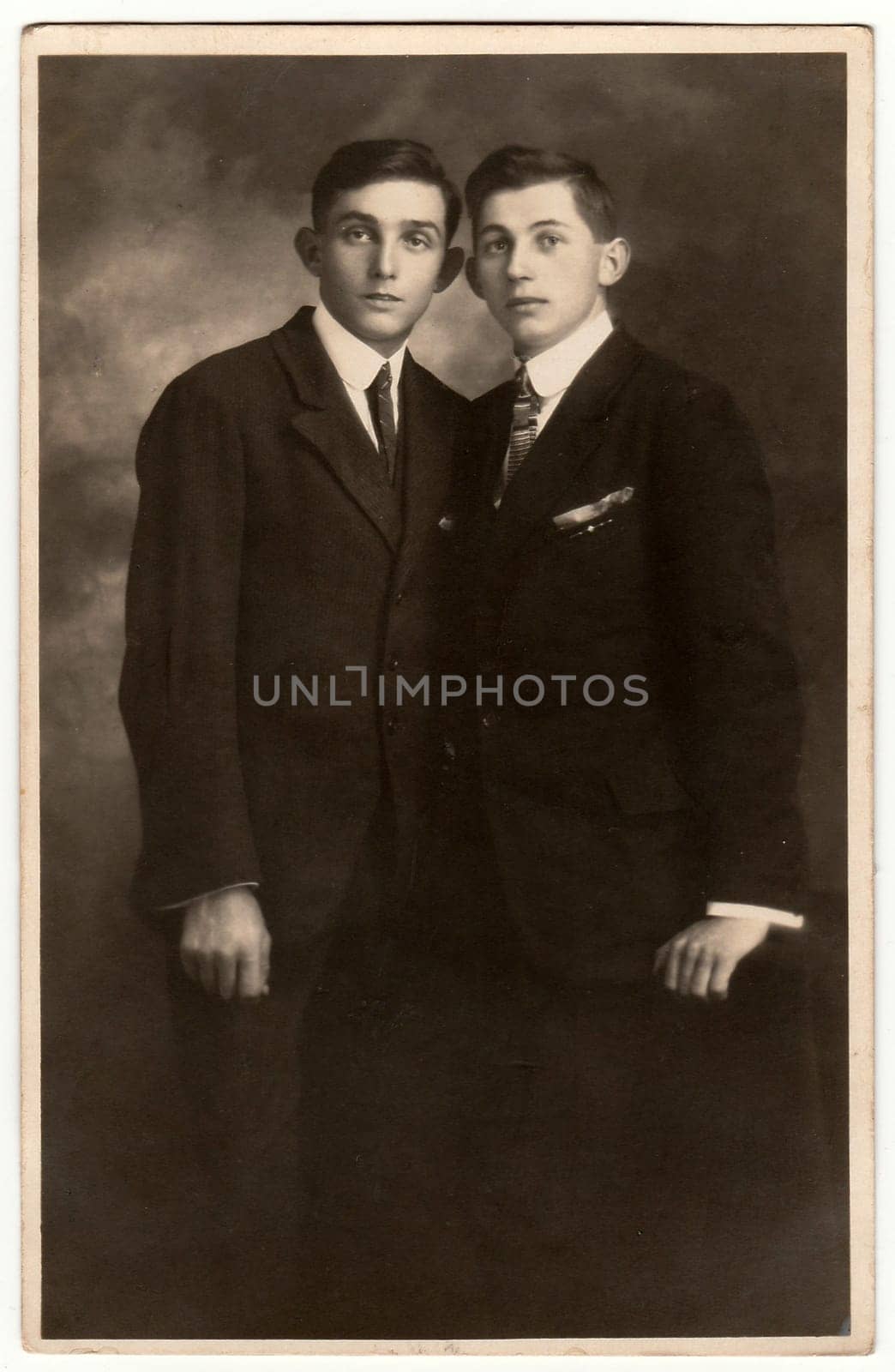 Vintage photo shows two young men pose in a photography studio. Antique black white photo. by roman_nerud