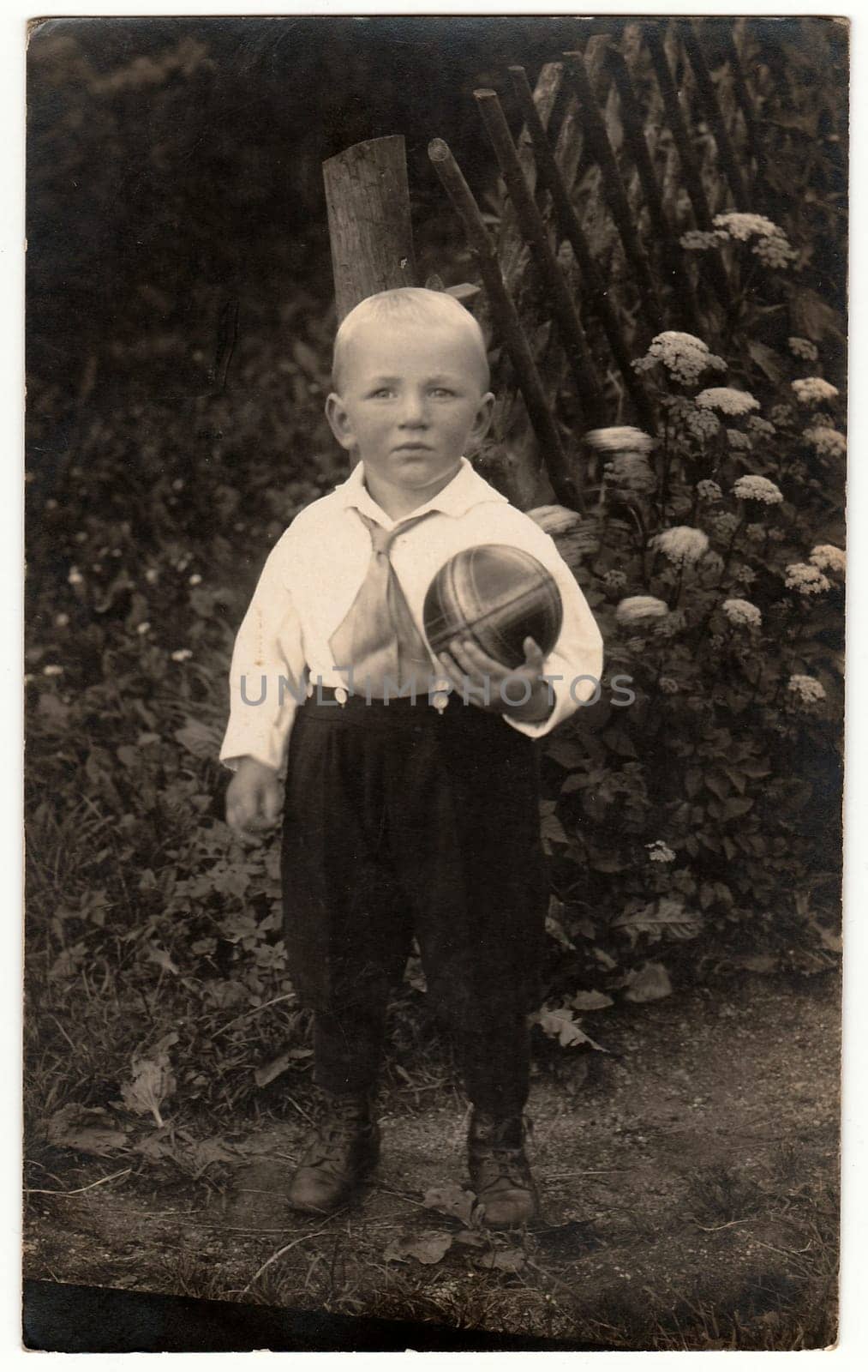 THE CZECHOSLOVAK REPUBLIC - CIRCA 1930s: Vintage photo shows a small boy with ball poses outdoors. Black white antique photo.