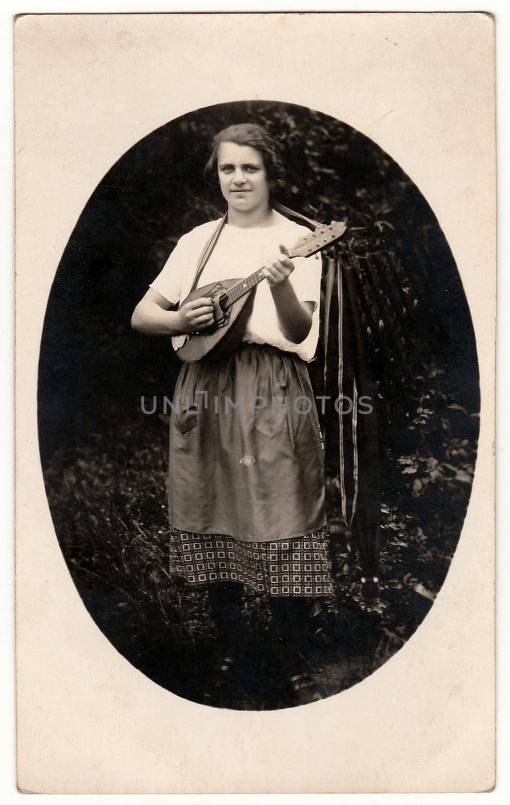 Vintage photo shows a woman plays the mandolin outdoors. Photo is oval shape. Black white antique photo. by roman_nerud