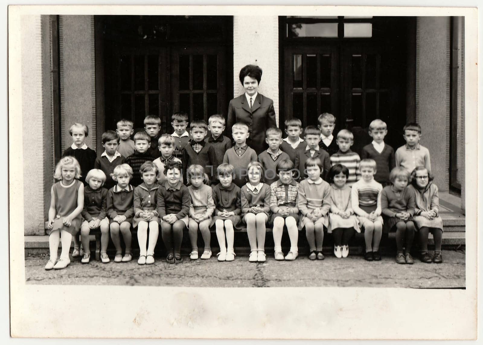 Vintage photo shows pupils schoolmates pose in front of school. Black white antique photo. by roman_nerud