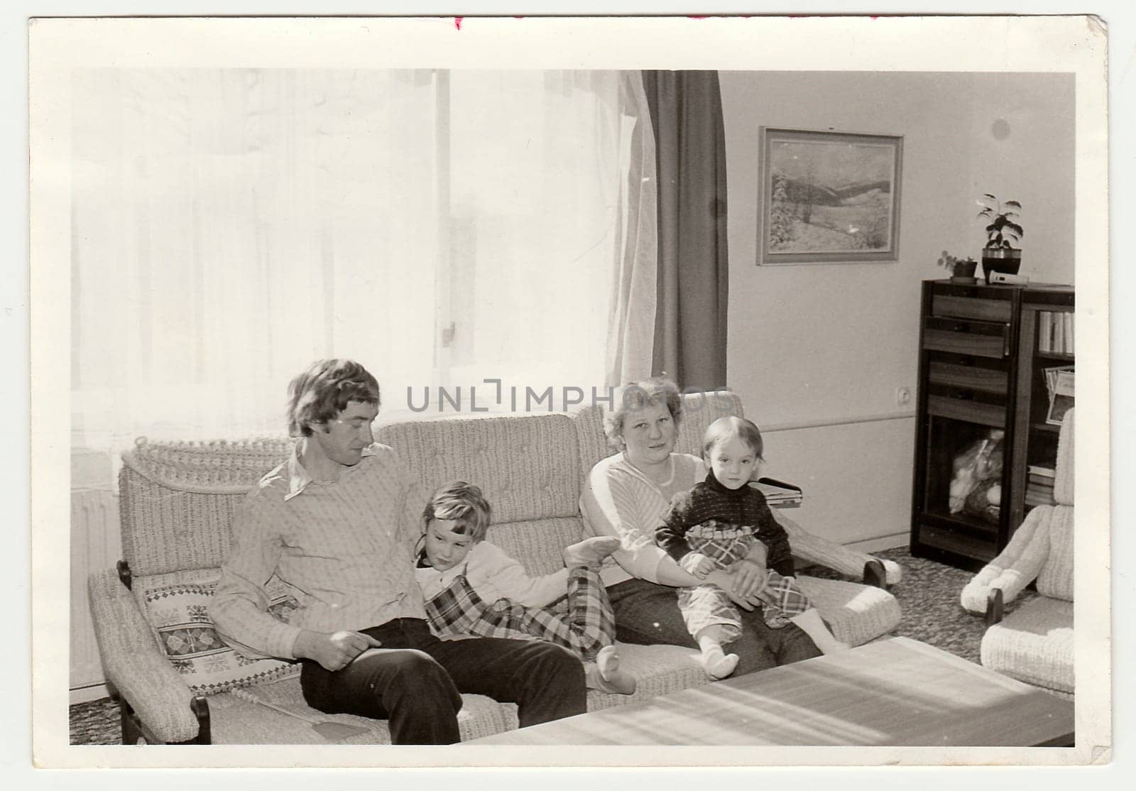 Vintage photo shows parents with their children in the living room. Antique black white photo. by roman_nerud