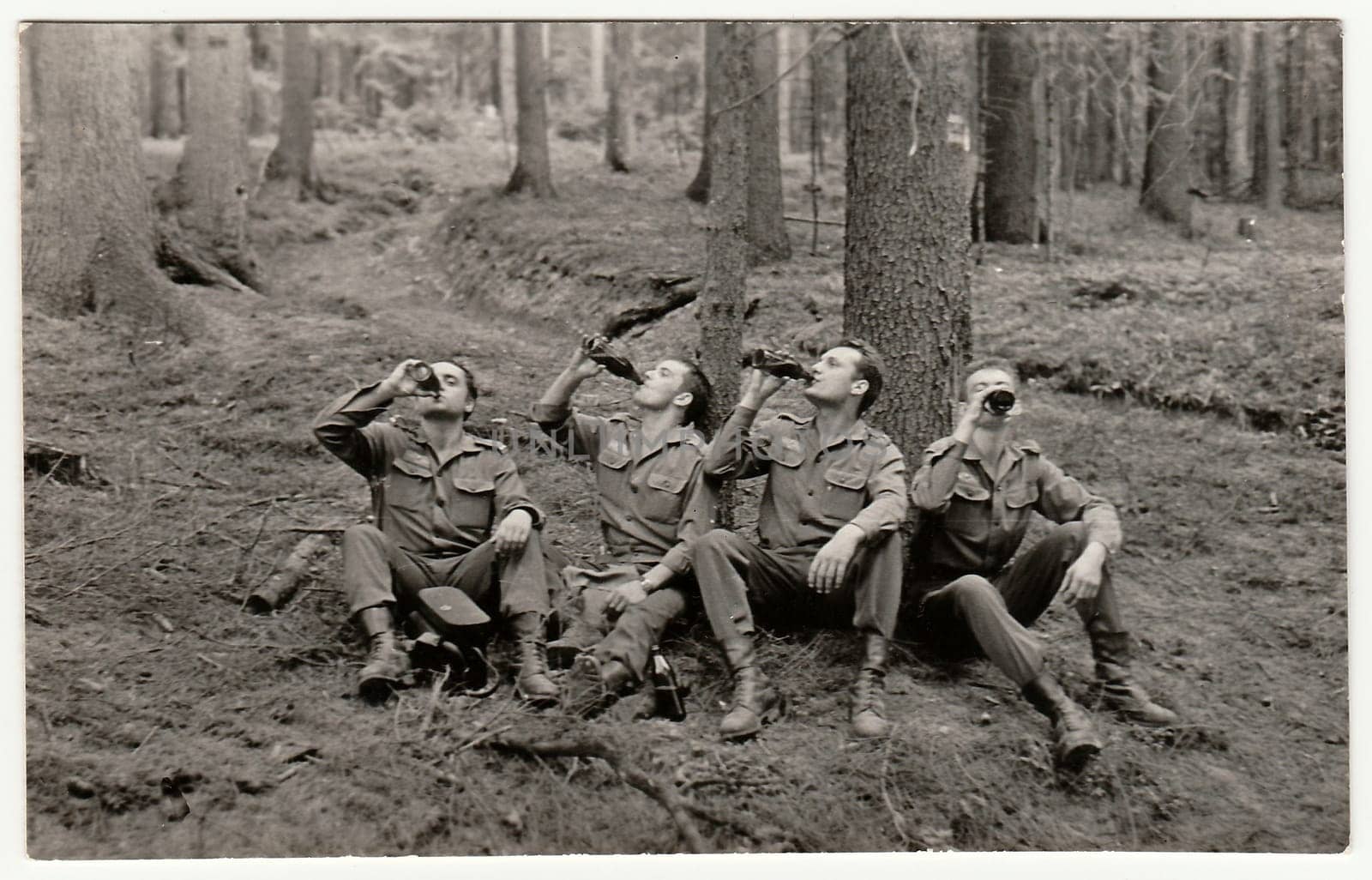 Vintage photo shows soldiers pose with beer bottles outddors. Black & white antique photo. by roman_nerud