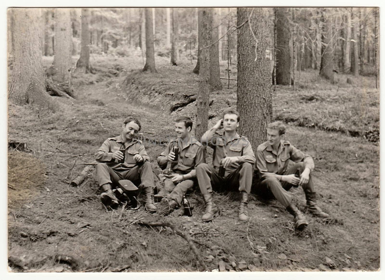 Vintage photo shows soldiers pose with beer bottles outdoors. Black & white antique photo. by roman_nerud