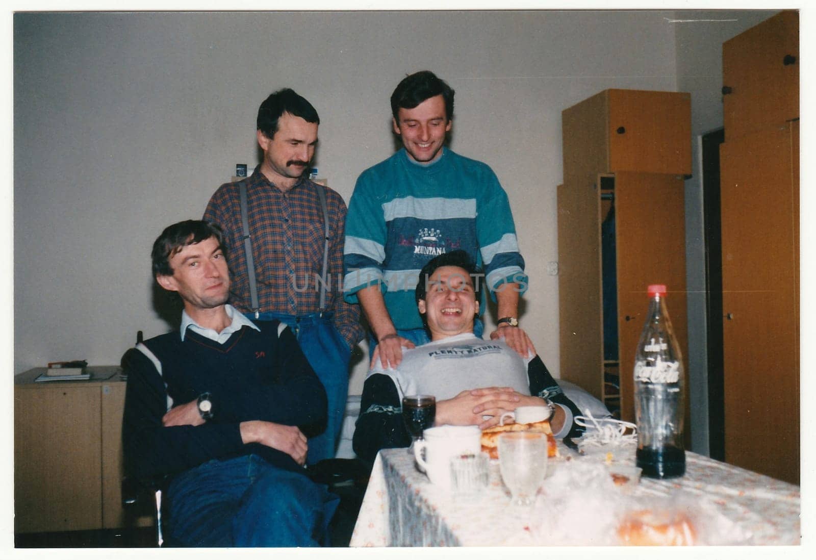 Vintage photo shows a group of men (workers) during party indoors. Colour photography. by roman_nerud