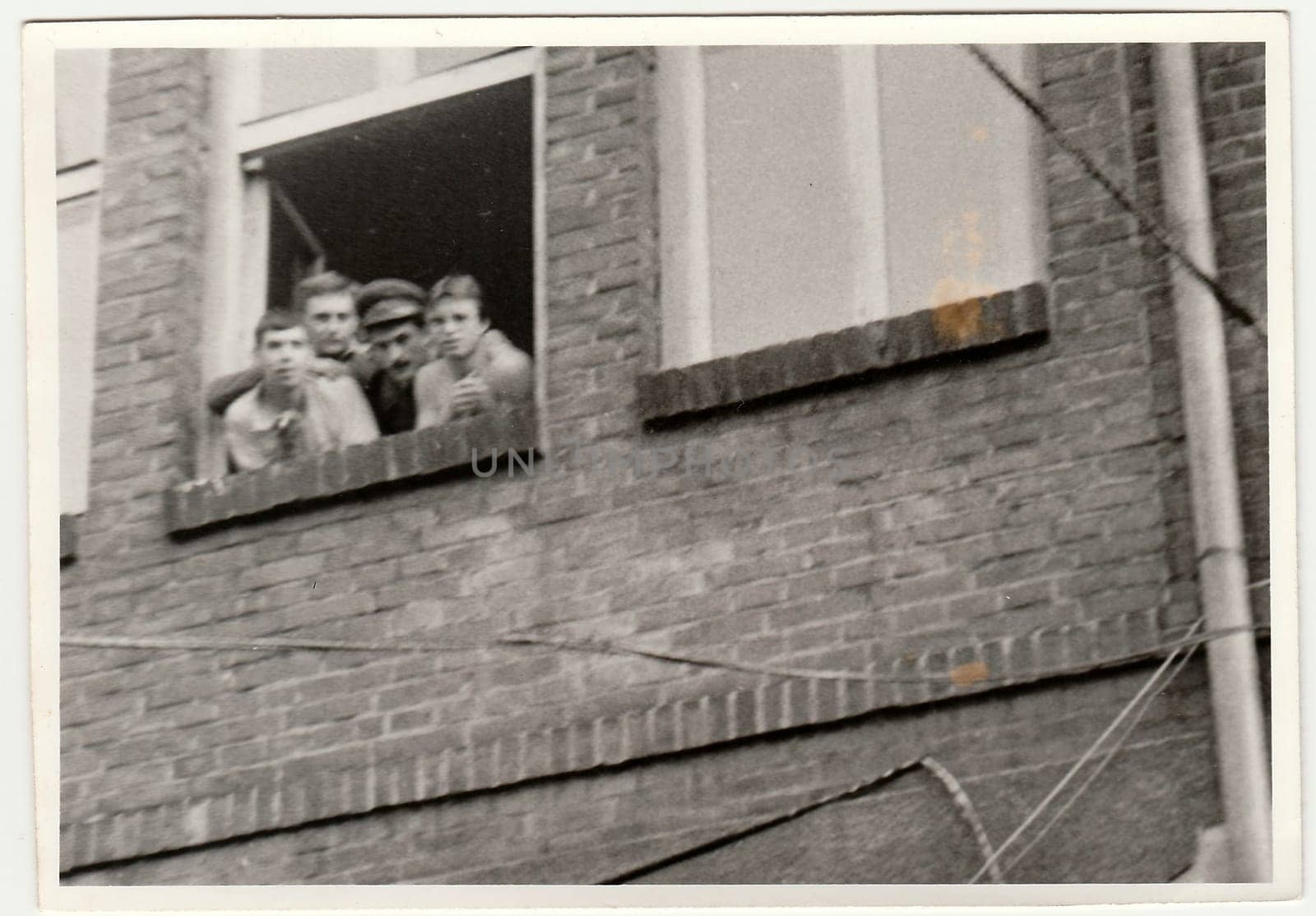 Vintage photo shows soldiers pose in barracks`s window. Black & white antique photography. by roman_nerud