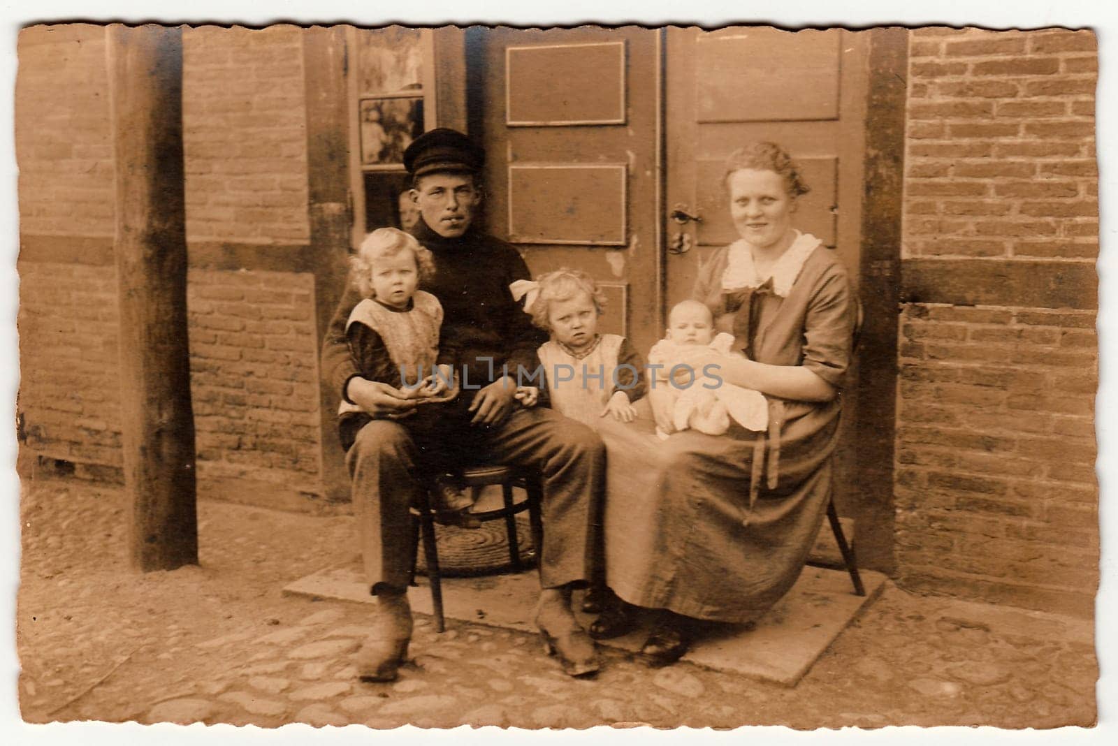 Vintage photo shows rural family sits in front of house. Black white antique photography. by roman_nerud
