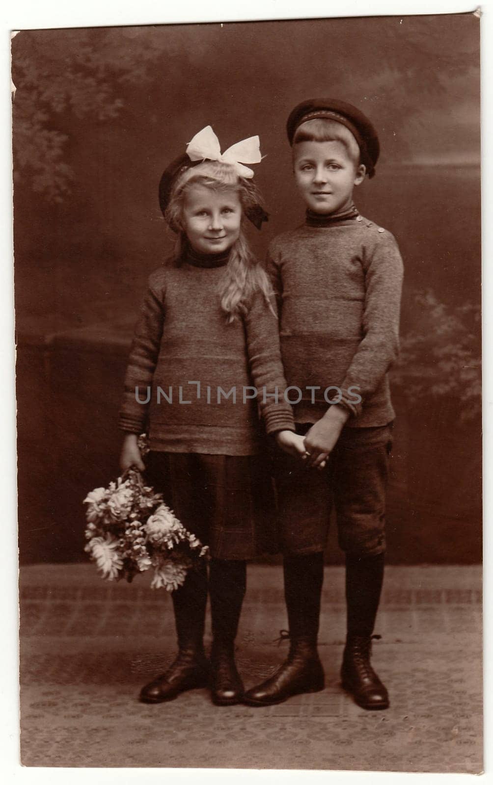 Vintage photo shows girl and boy siblings , girl wears white hair ribbon. Black white studio photography by roman_nerud