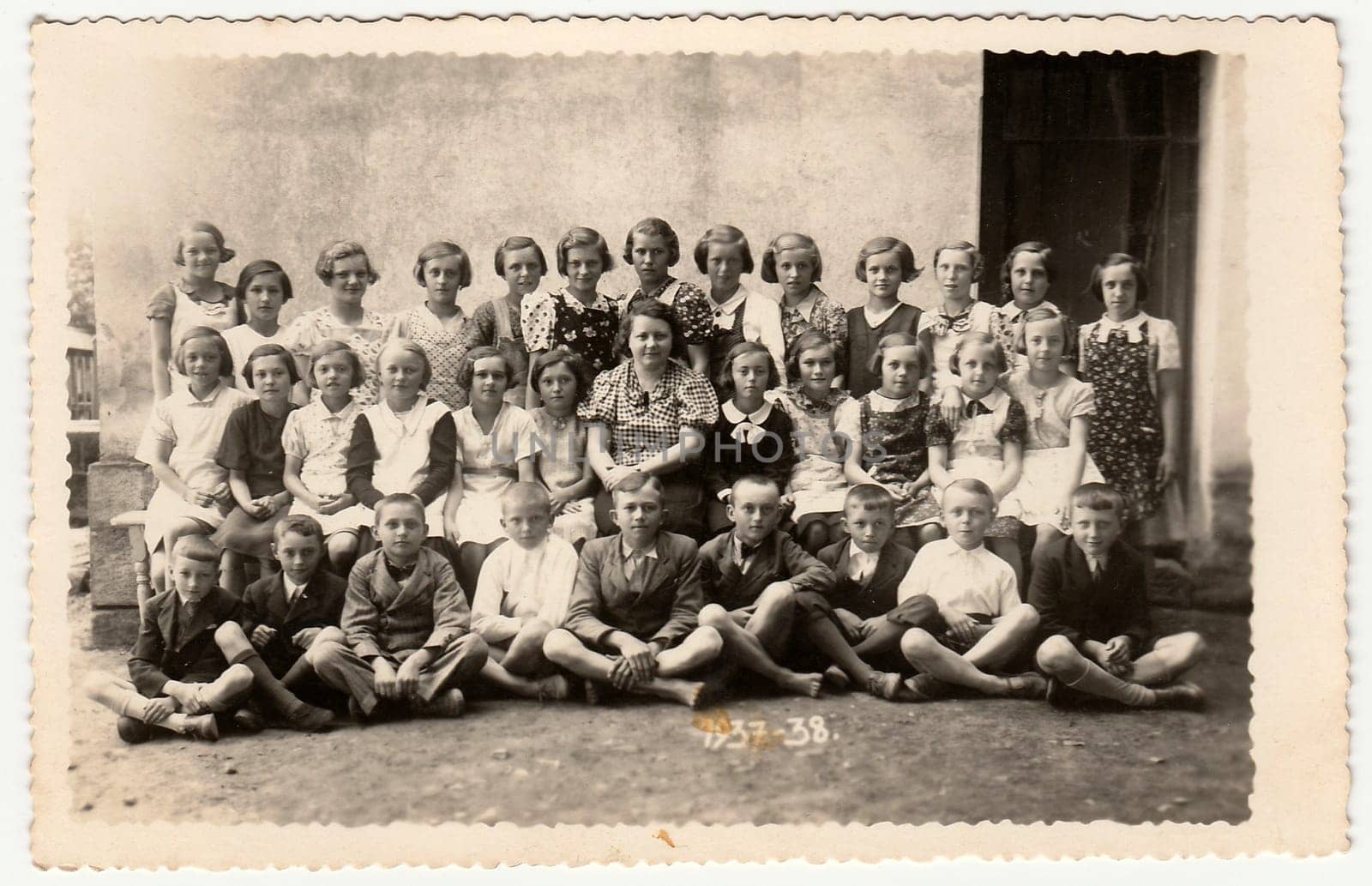 Vintage photo shows a group of schoolmates and female teacher. Black white photo. by roman_nerud