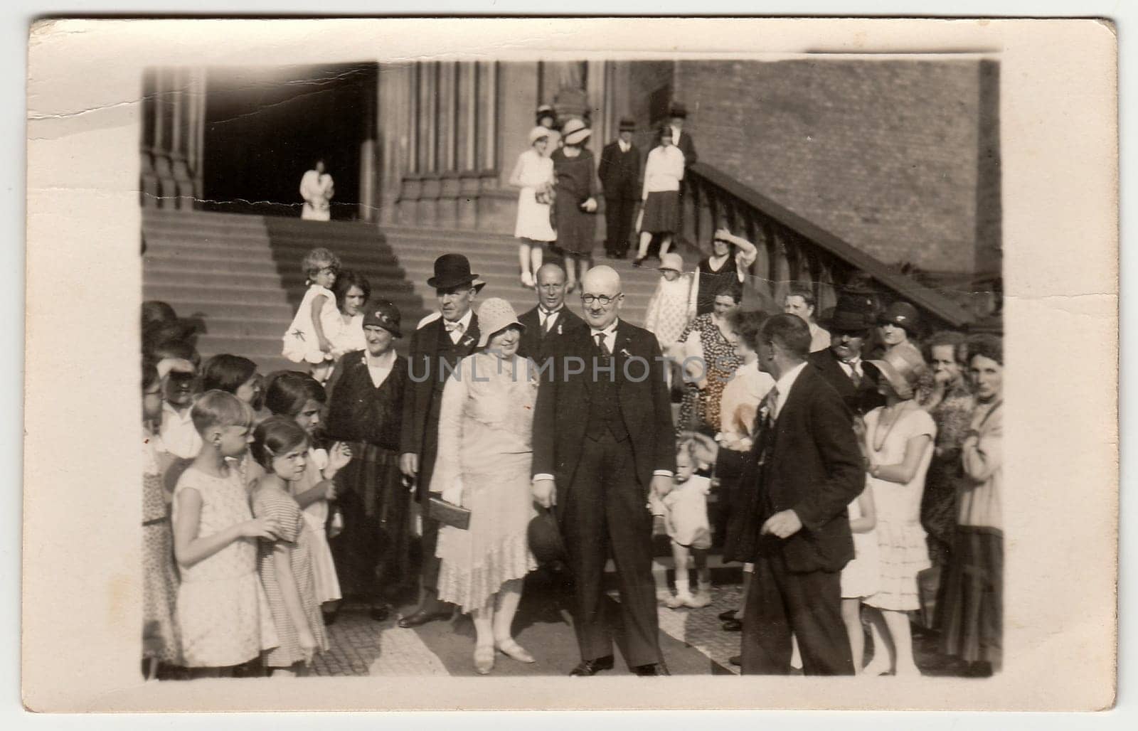 PRAGUE, THE CZECHOSLOVAK REPUBLIC - JUNE 28, 1930: Vintage photo shows elderly newlyweds in front of church after wedding ceremony. Black white antique photography.