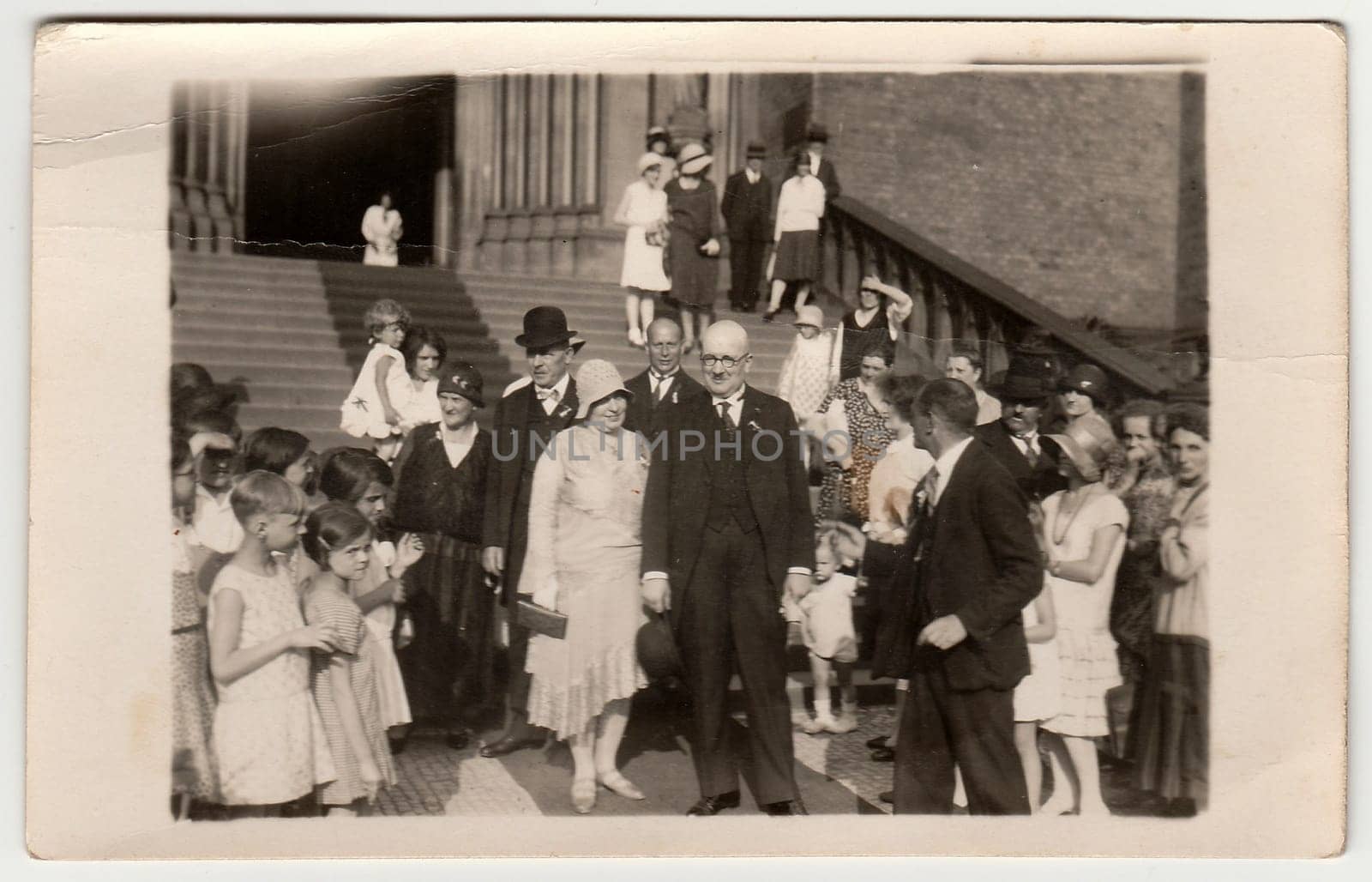 Vintage photo shows elderly newlyweds in front of church after wedding ceremony. Black white antique photography. by roman_nerud