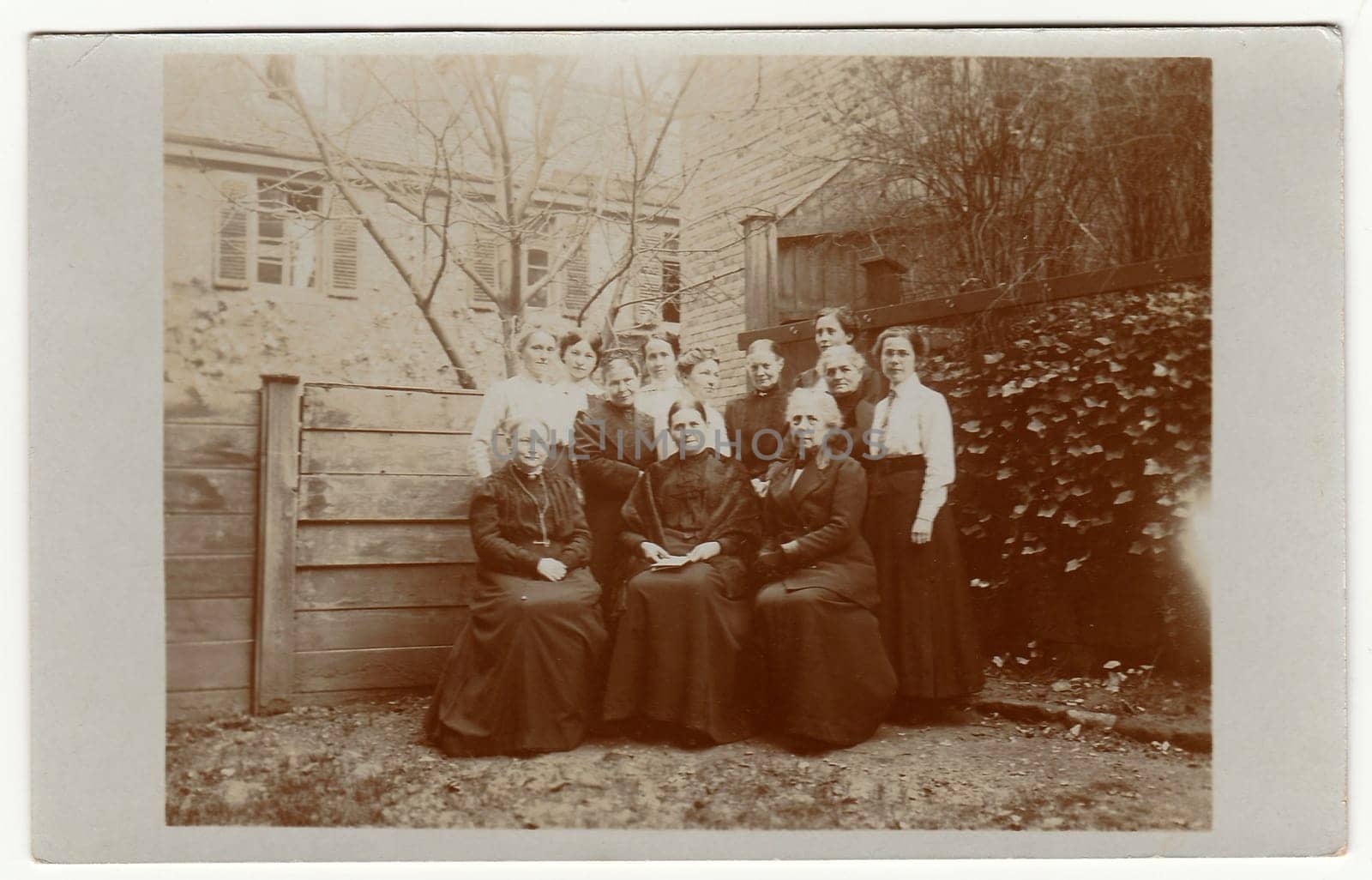 Vintage photo shows women pose in the back yard. Black white antique photography. by roman_nerud