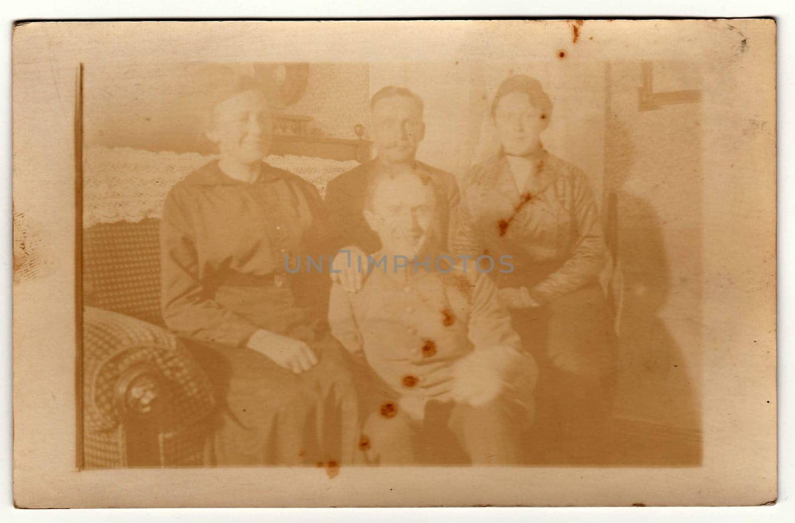 Vintage photo shows family at home. They sit on the sofa. Antique black white photography. Note: strong blurriness by roman_nerud