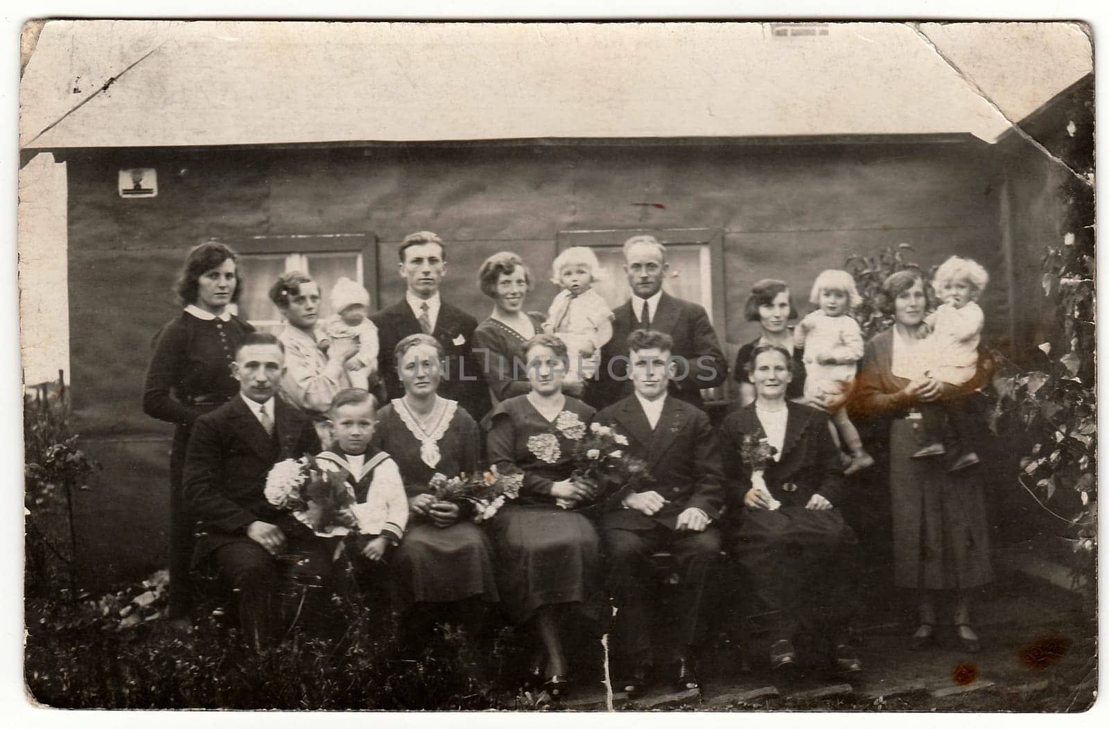 GERMANY - CIRCA 1940s: Vintage photo shows a big family poses behind house. Black white antique photography.