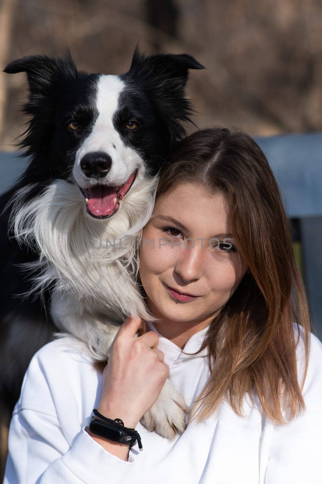 Caucasian woman hugging her dog Border Collie while sitting on a bench in autumn park