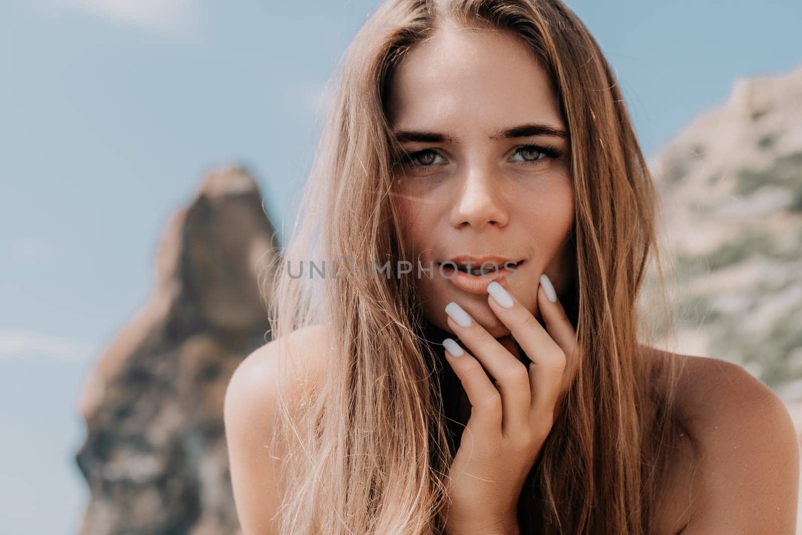 Woman travel sea. Young Happy woman in a long red dress posing on a beach near the sea on background of volcanic rocks, like in Iceland, sharing travel adventure journey