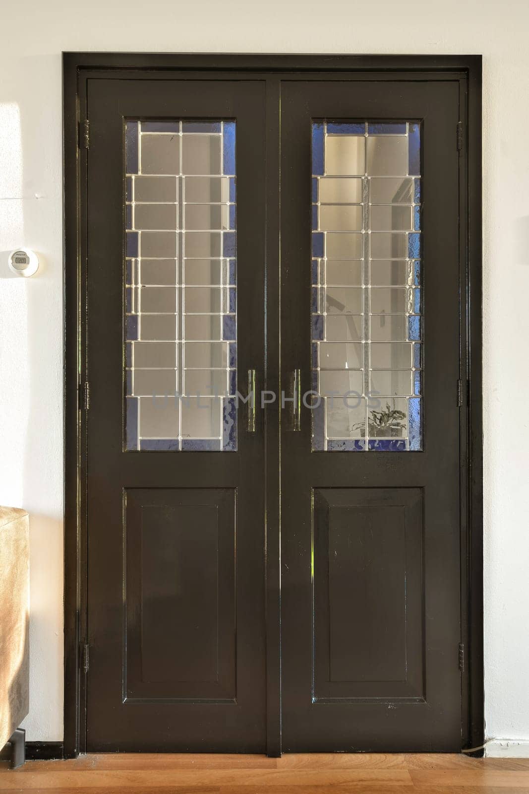 two black doors with glass panels on the top and bottom, in an entry way to a wall is behind them