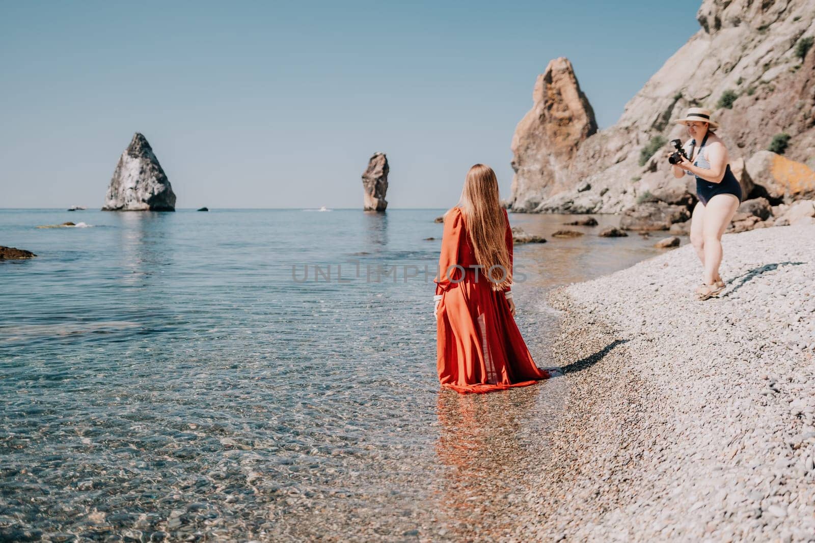 Woman travel sea. Happy tourist taking picture outdoors for memories. Woman traveler looks at the edge of the cliff on the sea bay of mountains, sharing travel adventure journey.