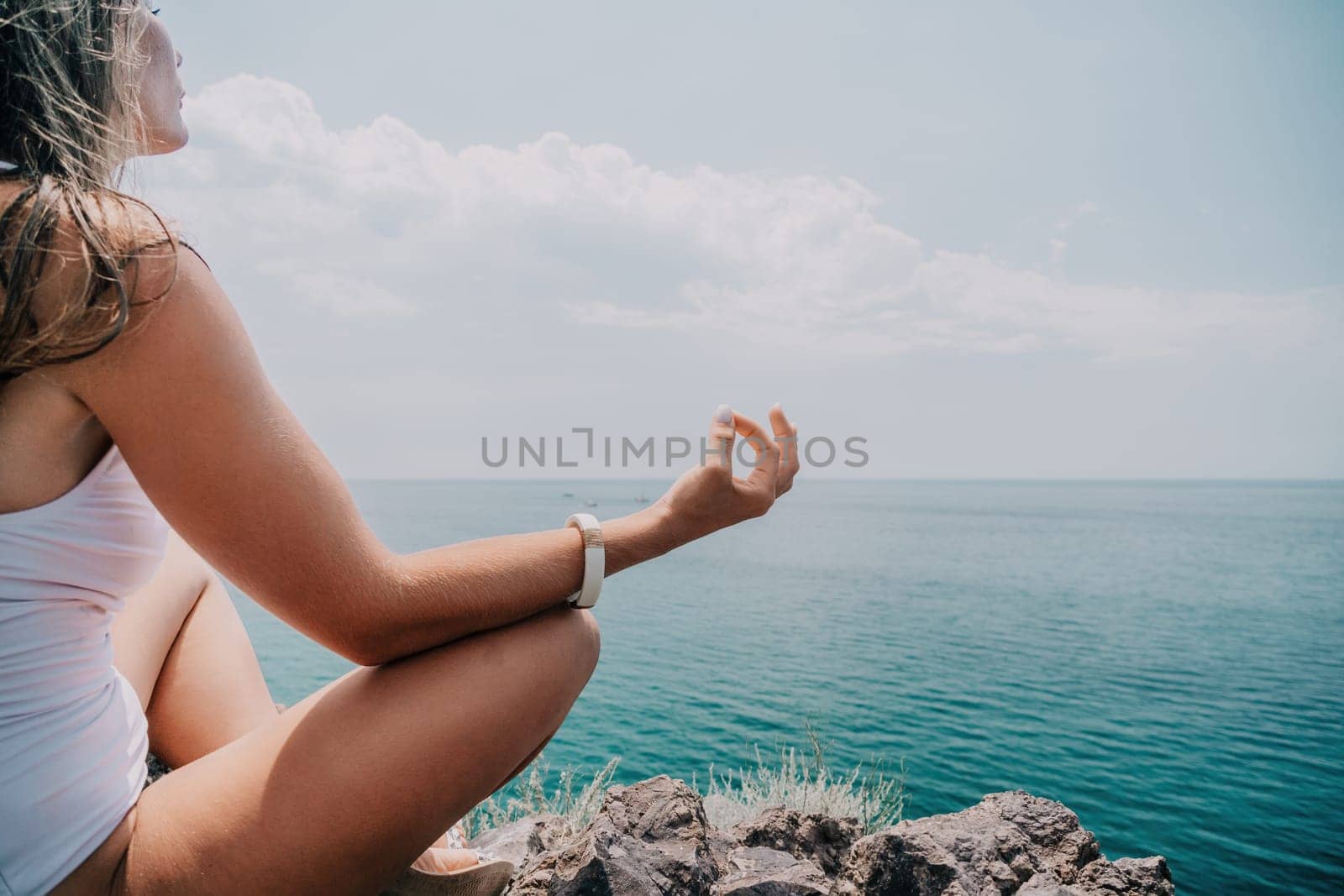 Woman meditating in yoga pose silhouette at the ocean, beach and rock mountains. Motivation and inspirational fit and exercising. Healthy lifestyle outdoors in nature, fitness concept.