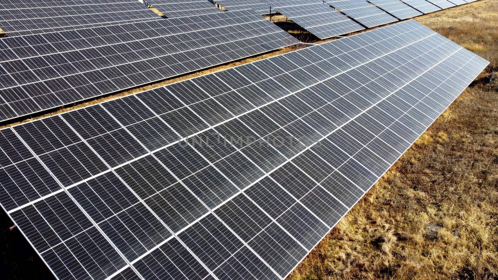 Solar power plant. Flight over the modules of solar power station on sunny day by Mari1408